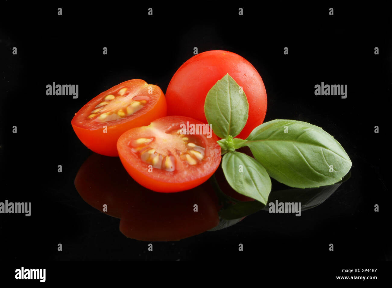 Tomatoes and basil with reflections on a black background Stock Photo ...
