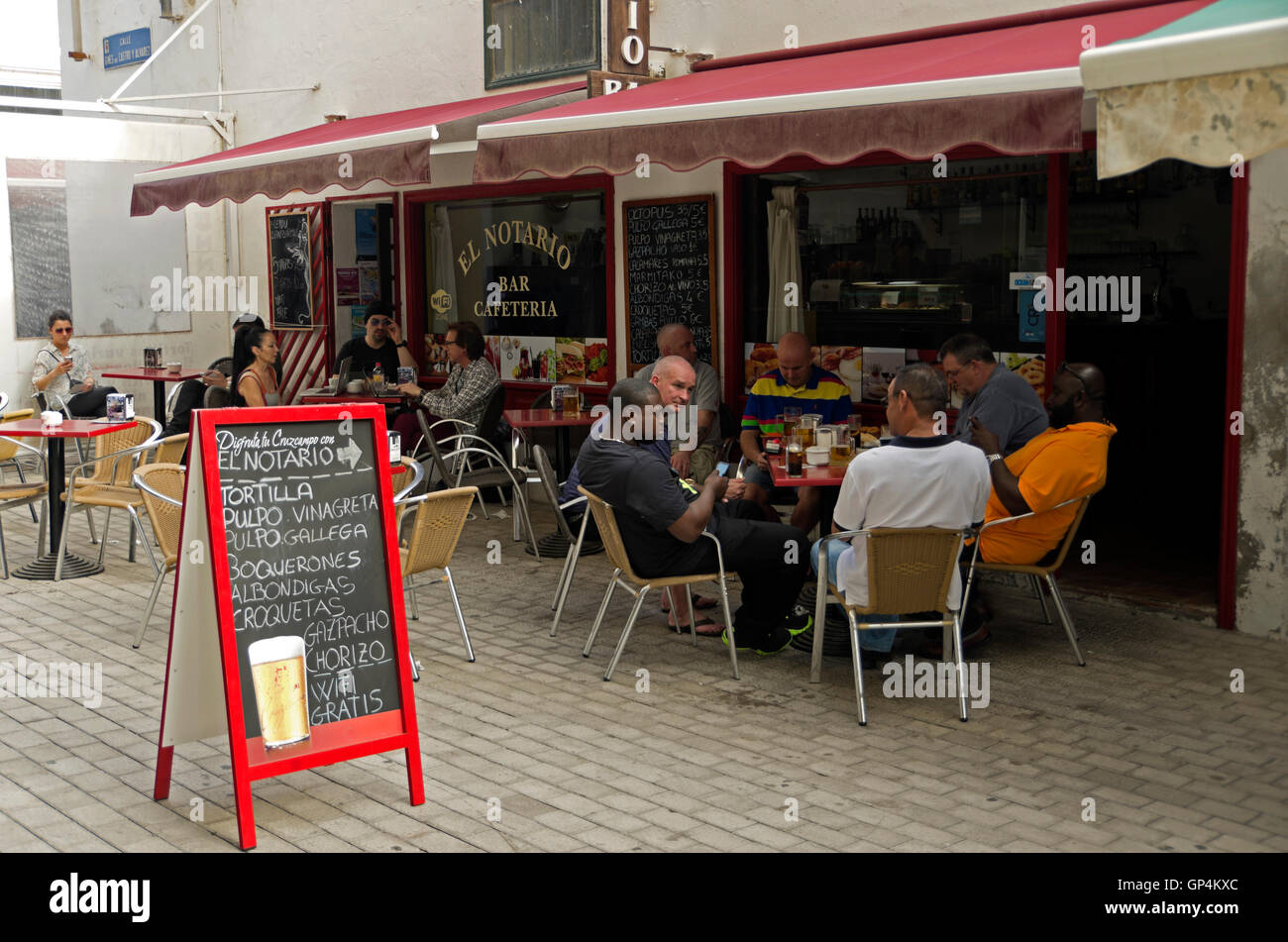 Men and women eating lunch at sidewalk cafes. Mobil phones in use by tourist at tables. Stock Photo