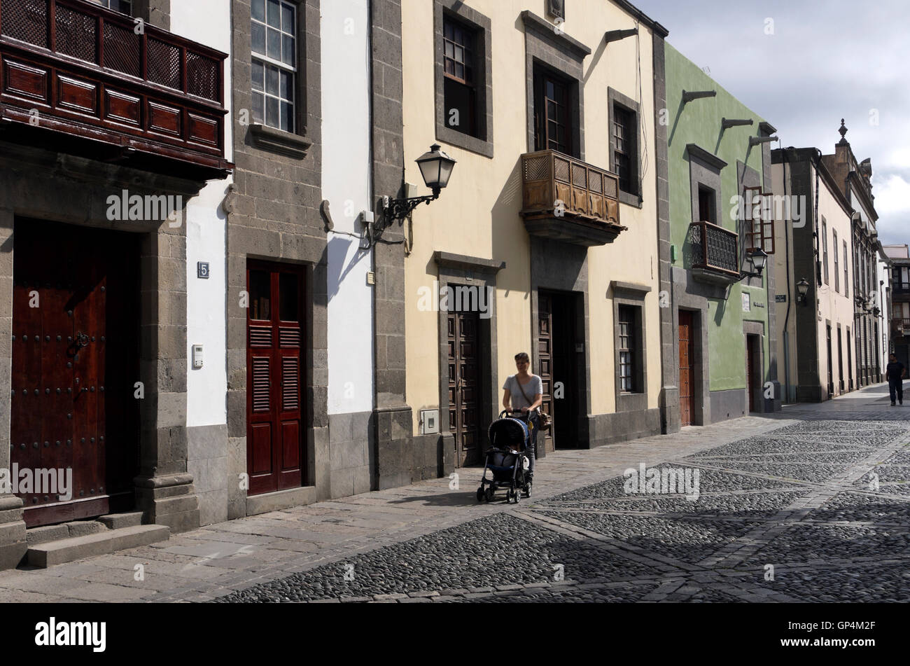 Woman pushing stroller walkes past historic 14th century buildings in Vegueta Neighborhood. Stock Photo