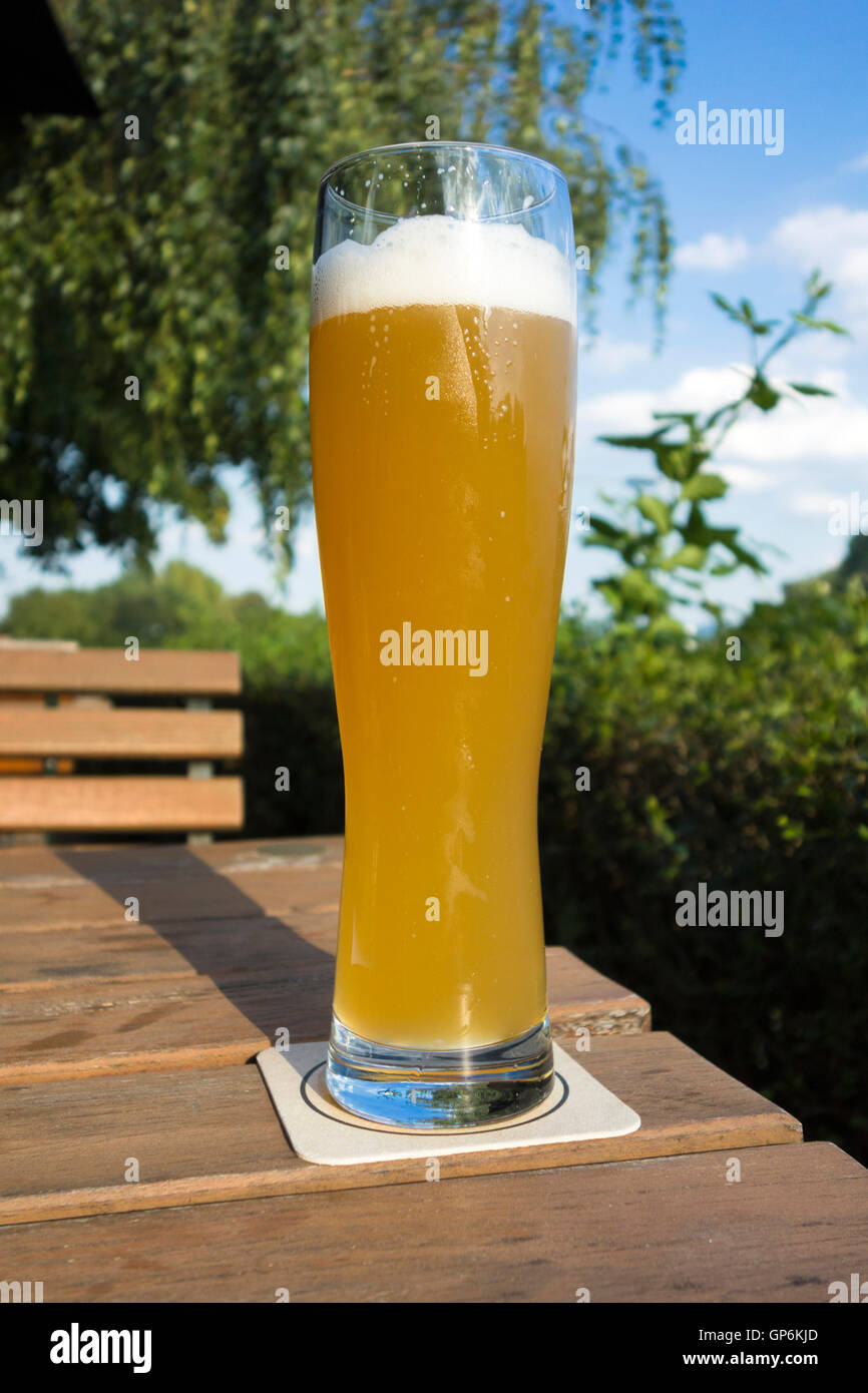 Two tall elegant pint glasses of cold wheat beer with a frothy head on a  wooden bar table conceptual of Oktoberfest Stock Photo - Alamy