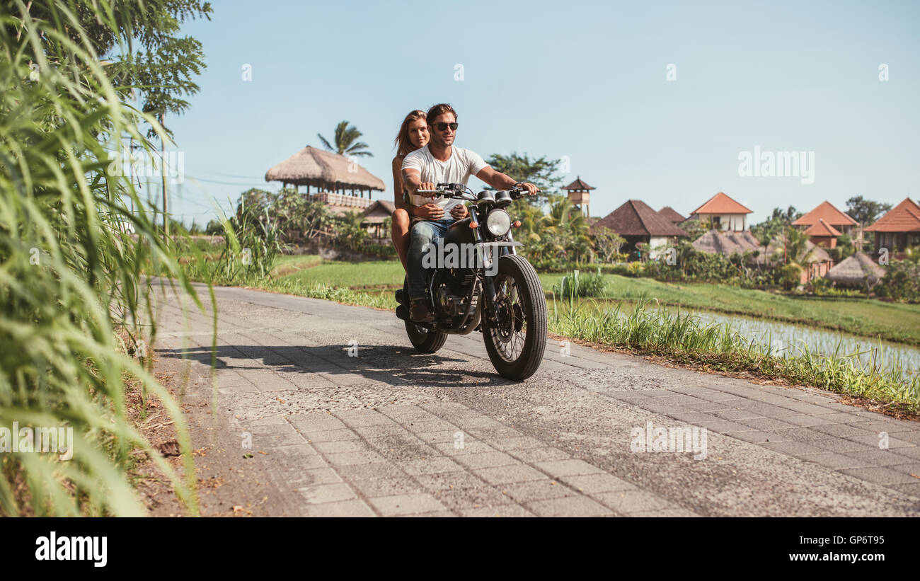 Young couple riding motorcycle on rural road. Young man and woman ...