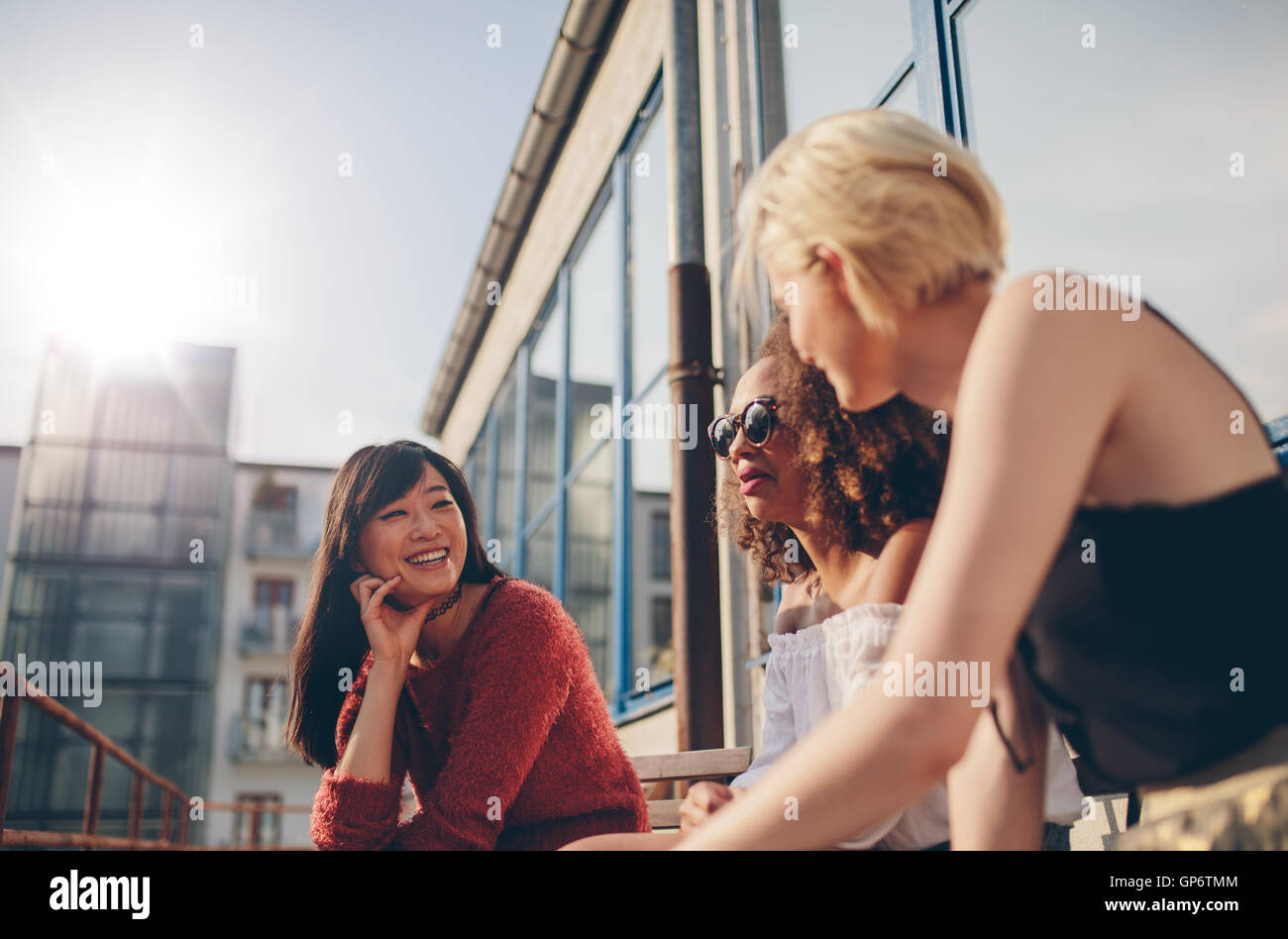 Group of female friends talking in a terrace. Three young women meeting at outdoor cafe chatting and enjoying. Stock Photo