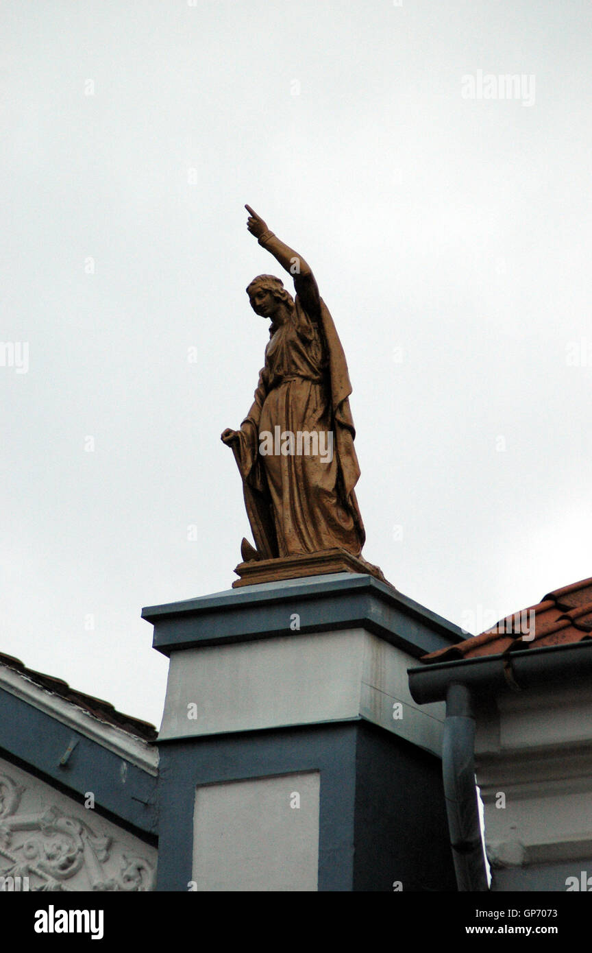 Two small statues at the top of a building, they stand here for a century, yet hardly anybody ever notice them. Stock Photo
