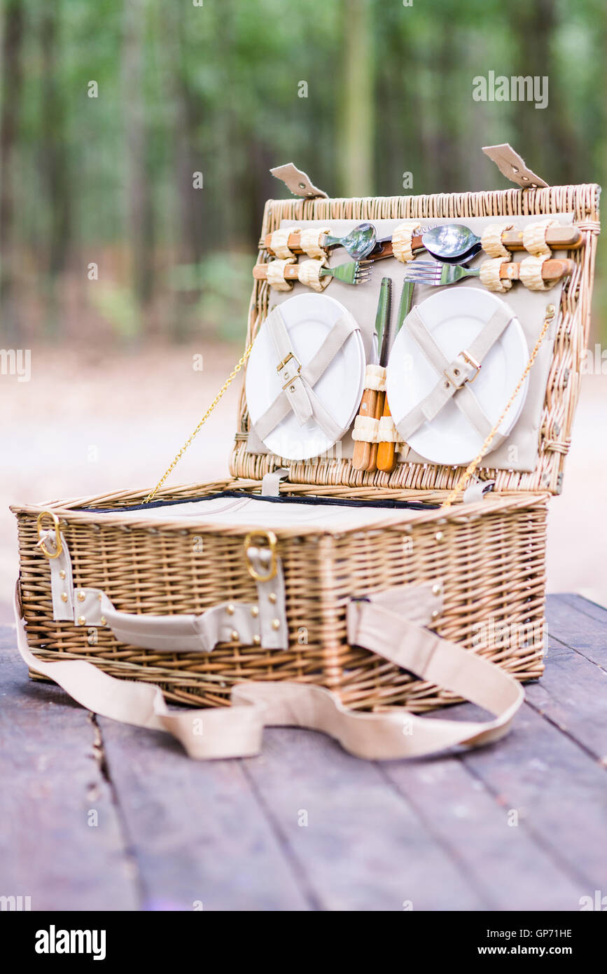Close up of an open picnic basket over wooden table in the park. Stock Photo