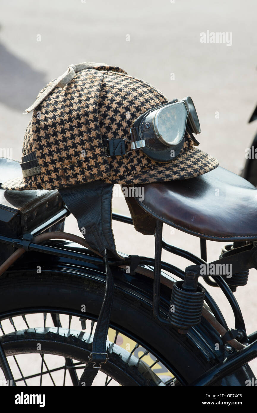 Old vintage motorcycle deerstalker head gear and goggles on a vintage motorcycle. UK Stock Photo
