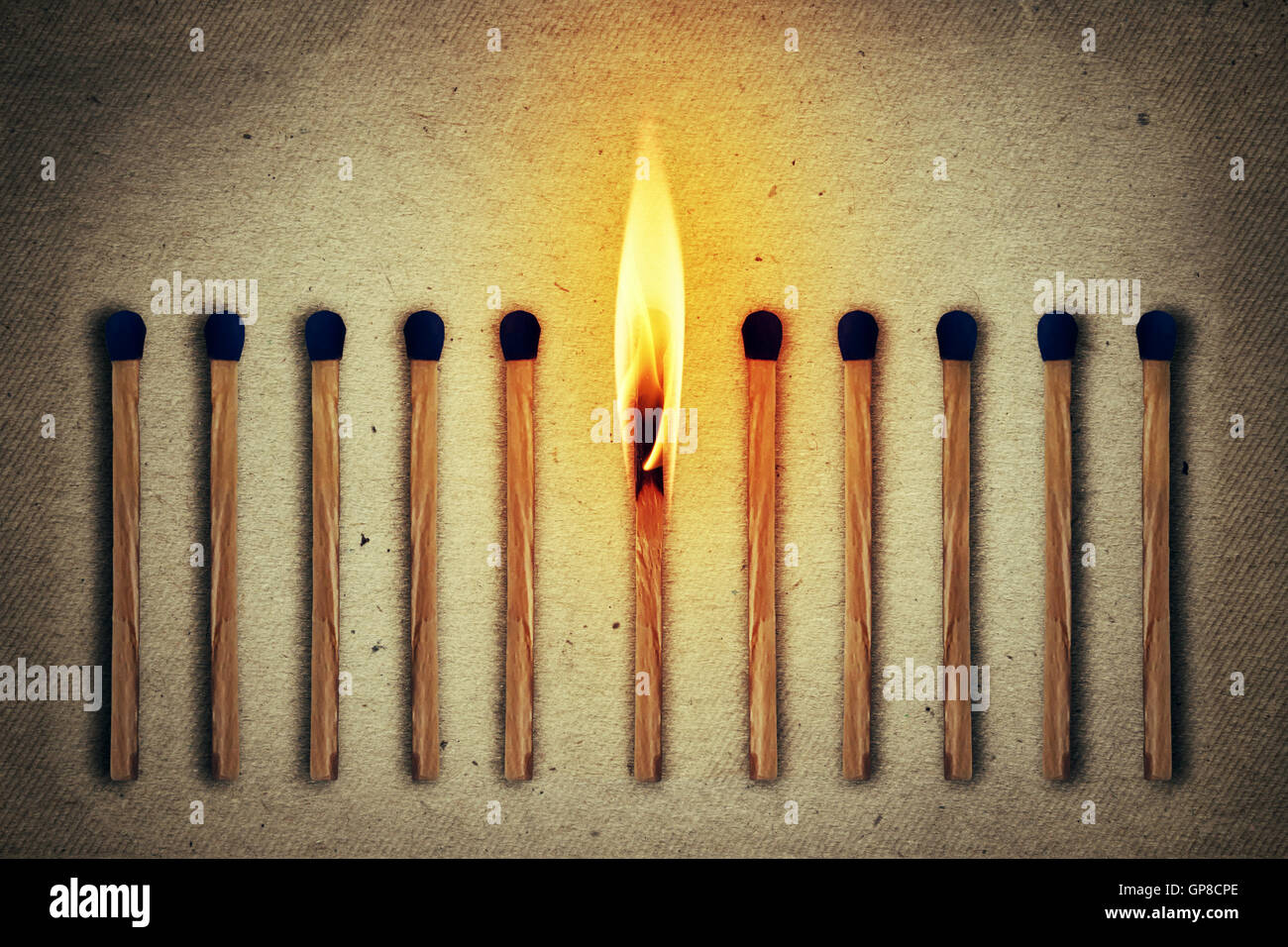 Burning match standing middle a row of whole, new matches Stock Photo