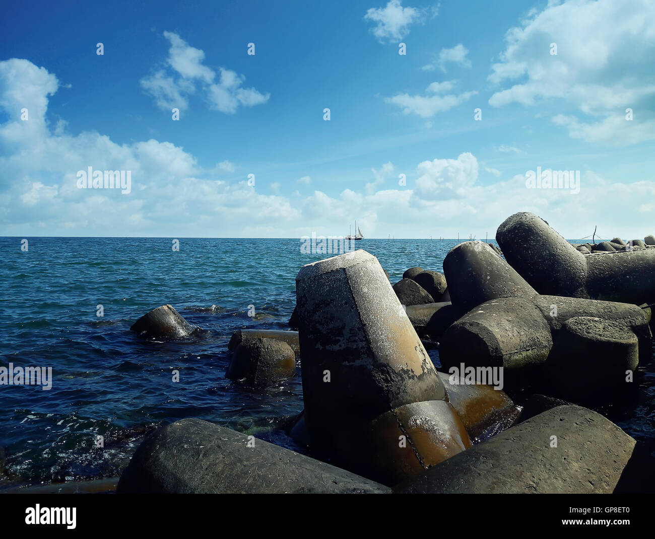 Huge stones in the sea water near the harbor at Balchik city, Bulgaria. Summer vacation background with a ship floating on far. Stock Photo