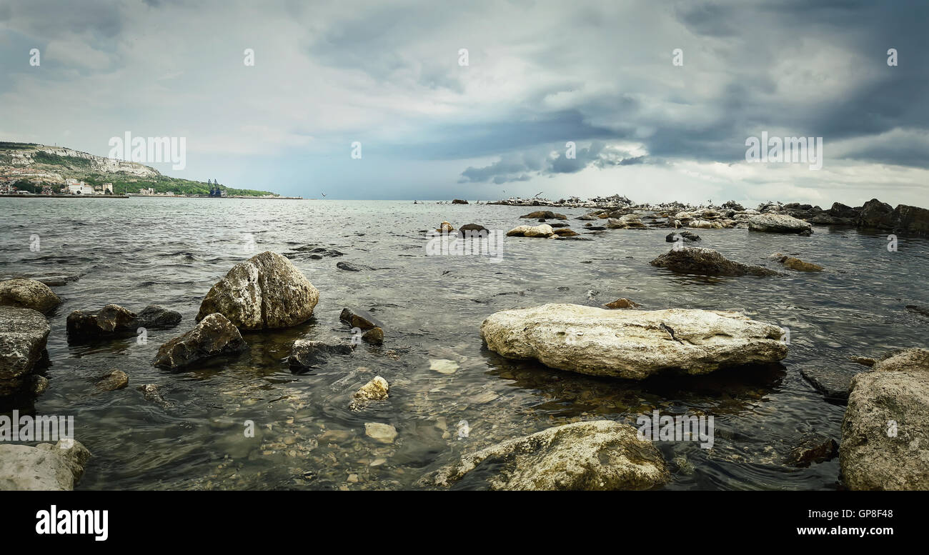 Seascape of stone beach with a dramatic cloudy sky. Beautiful view at the coast of the Black Sea in Balchik city, Bulgaria. Stock Photo