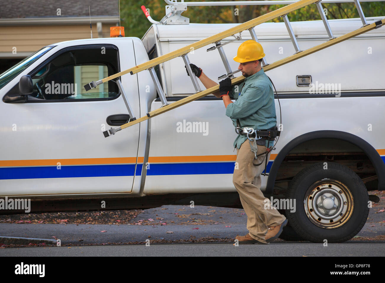 Lineman taking ladder from truck at site Stock Photo - Alamy