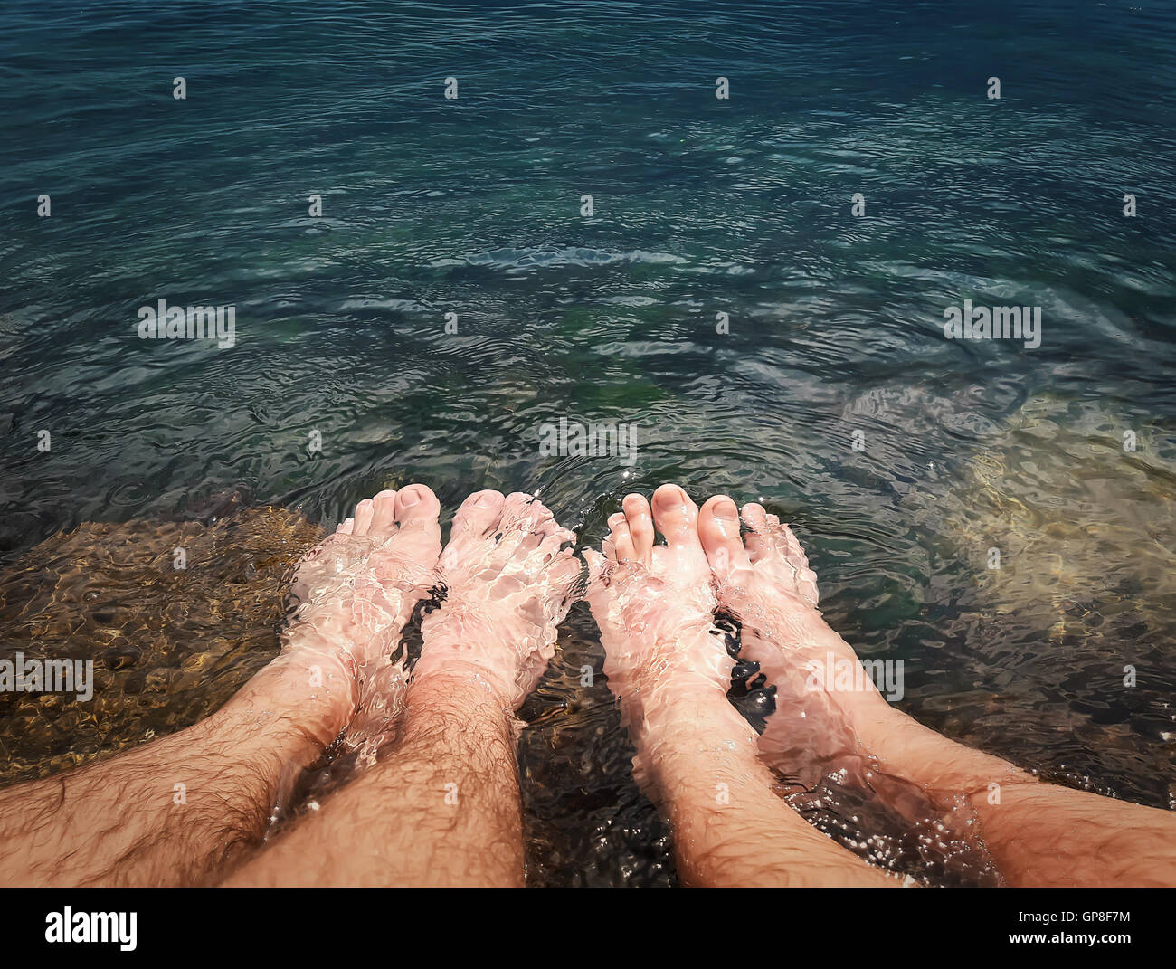 Close up of two male legs in the clear sea water. Summer vacation, resting and relaxation concept Stock Photo