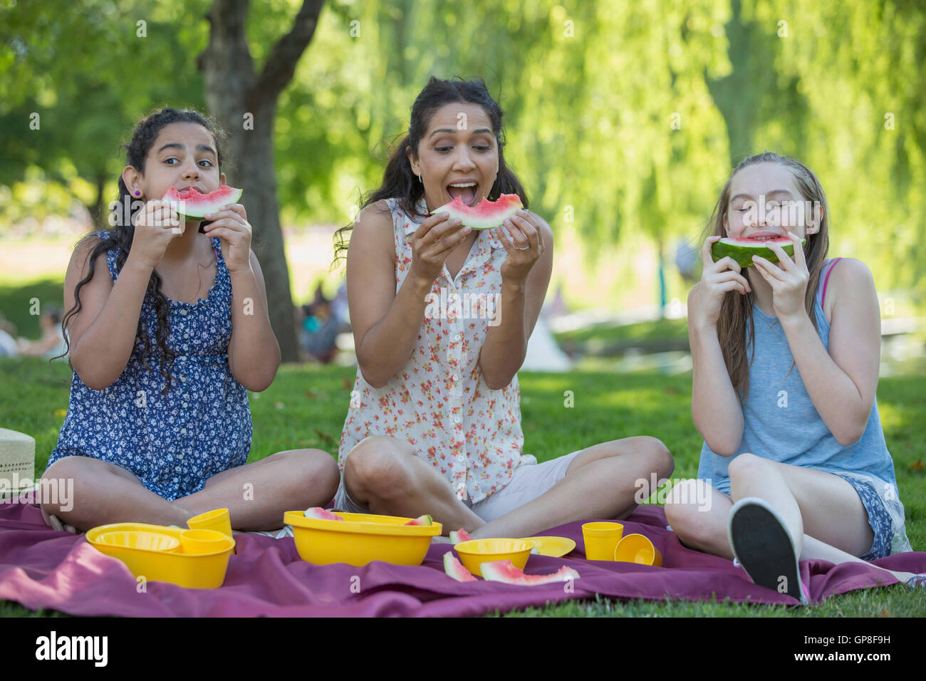 Happy Hispanic family having a picnic and eating watermelon in a park Stock Photo