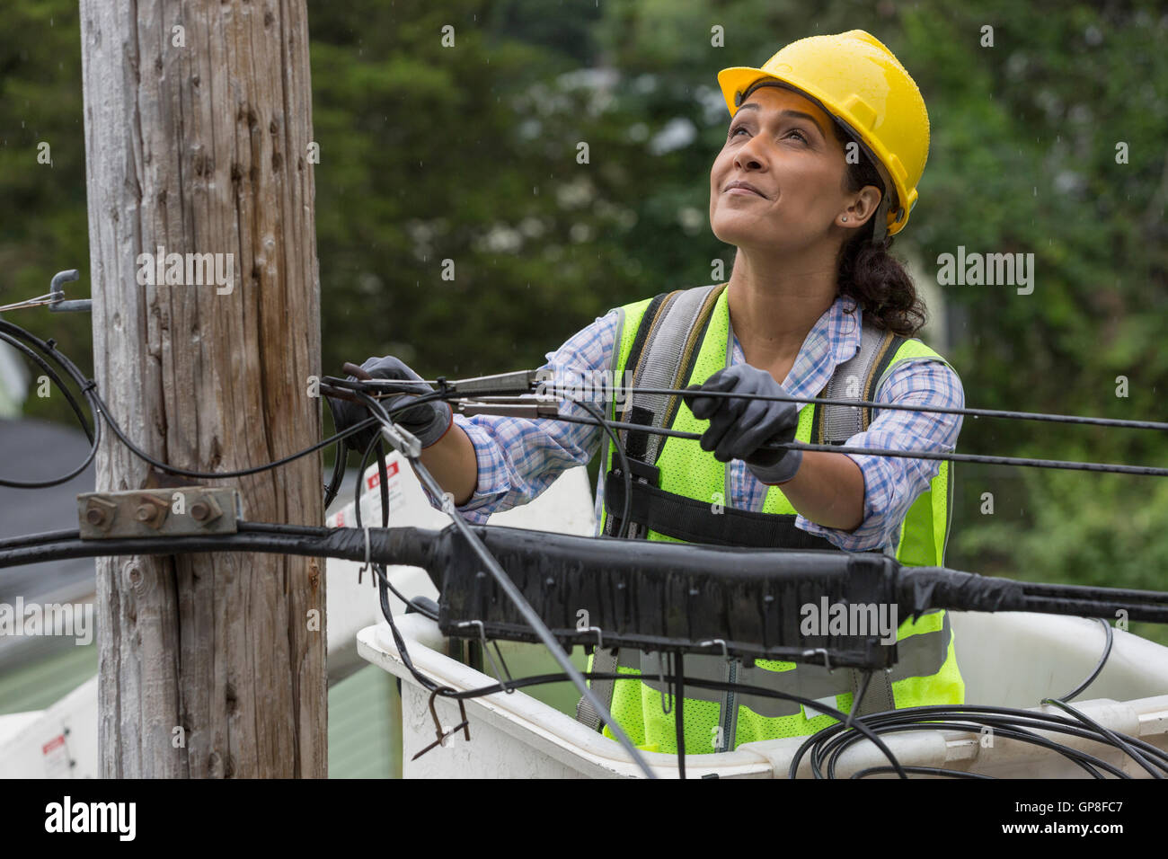 Hispanic female cable lineman examining the cables in bucket lift Stock ...