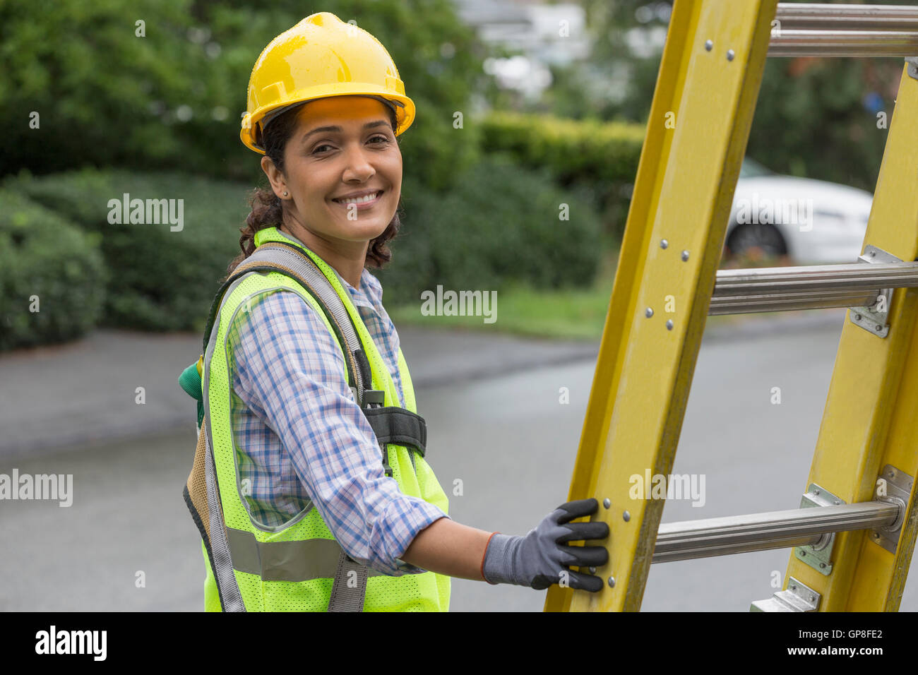 Portrait of happy Hispanic female lineman working on power line at site Stock Photo