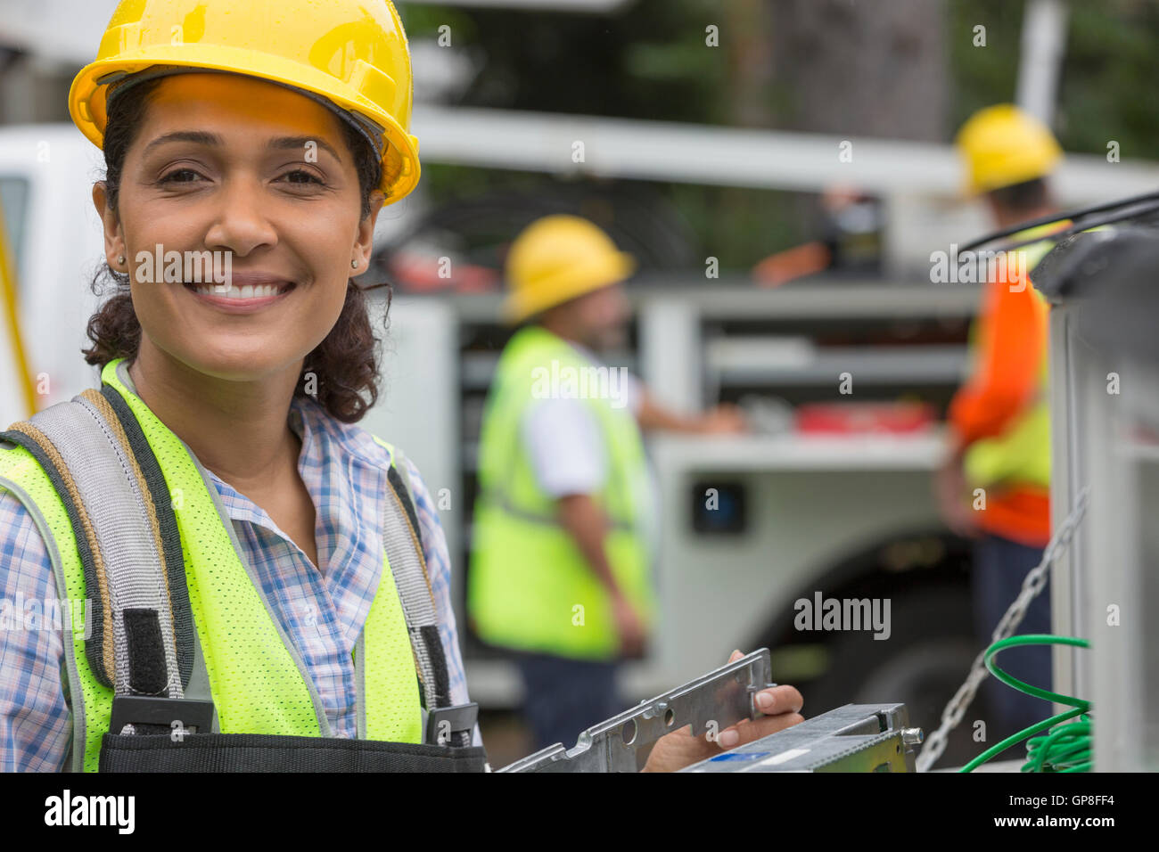 Portrait of happy Hispanic female utility worker working with line amplifiers at site Stock Photo