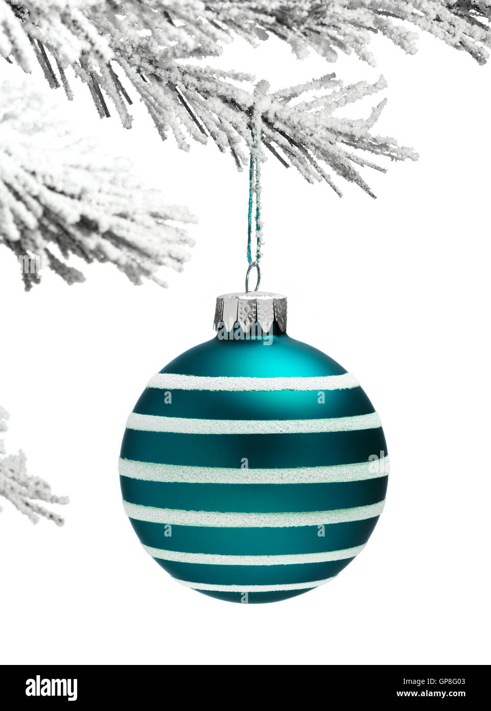 Snow covered Christmas tree with a blue Bauble hanging on a white background Stock Photo