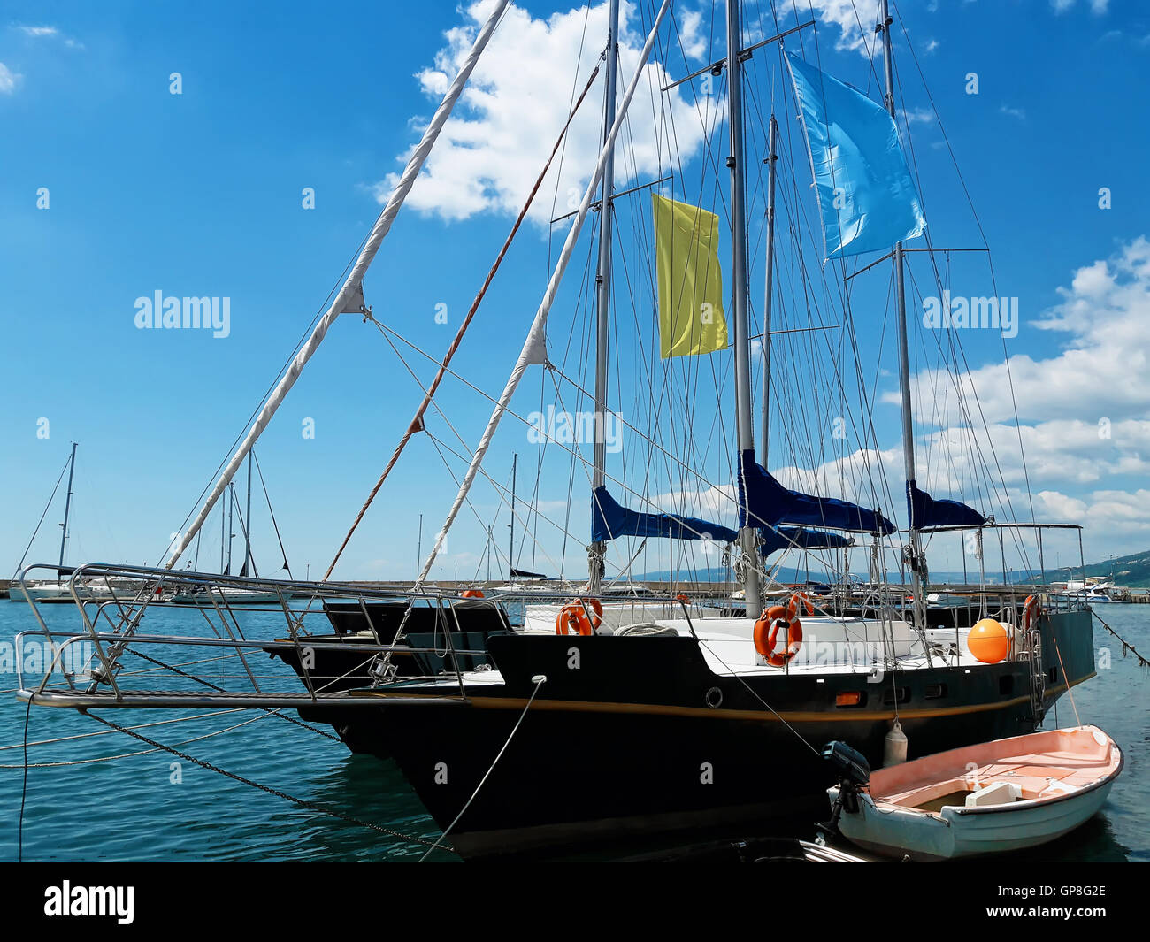 Sail ship with a small boat standing in water near the harbor Stock Photo