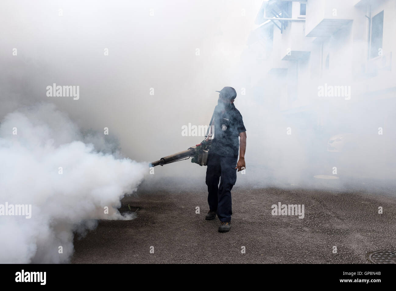 A worker fogs against mosquitoes around a condo in Kuala Lumpur, Malaysia. Stock Photo