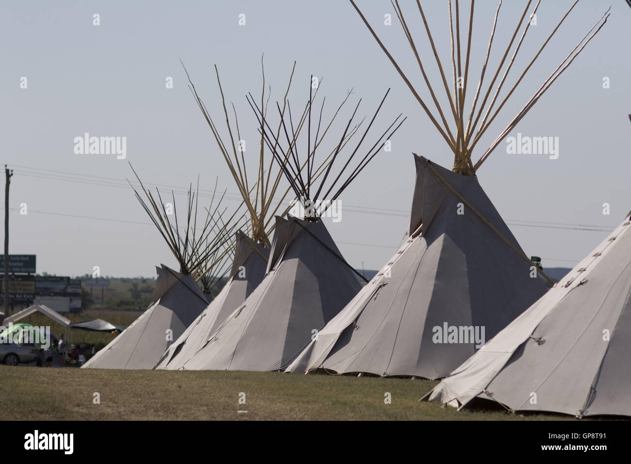 Elgin, Florida, USA. . Traditional tipis line the parking lot at the Comanche Nation headquarters as people play hand game during the Comanche fair in Elgin, Oklahoma. The two teams playing hand game can vary in size, each team (the ''hiding'' team and the ''guessing'' team) must have a captain. The game is played with two pairs of 'bones', each pair consisting of one plain and one striped bone. Each tribe decides which bone will be guessed, the plain or striped bone. Oklahoma indians generally call for the striped bone. The two teams, one ''hiding'' and one ''guessing, '' si Stock Photo