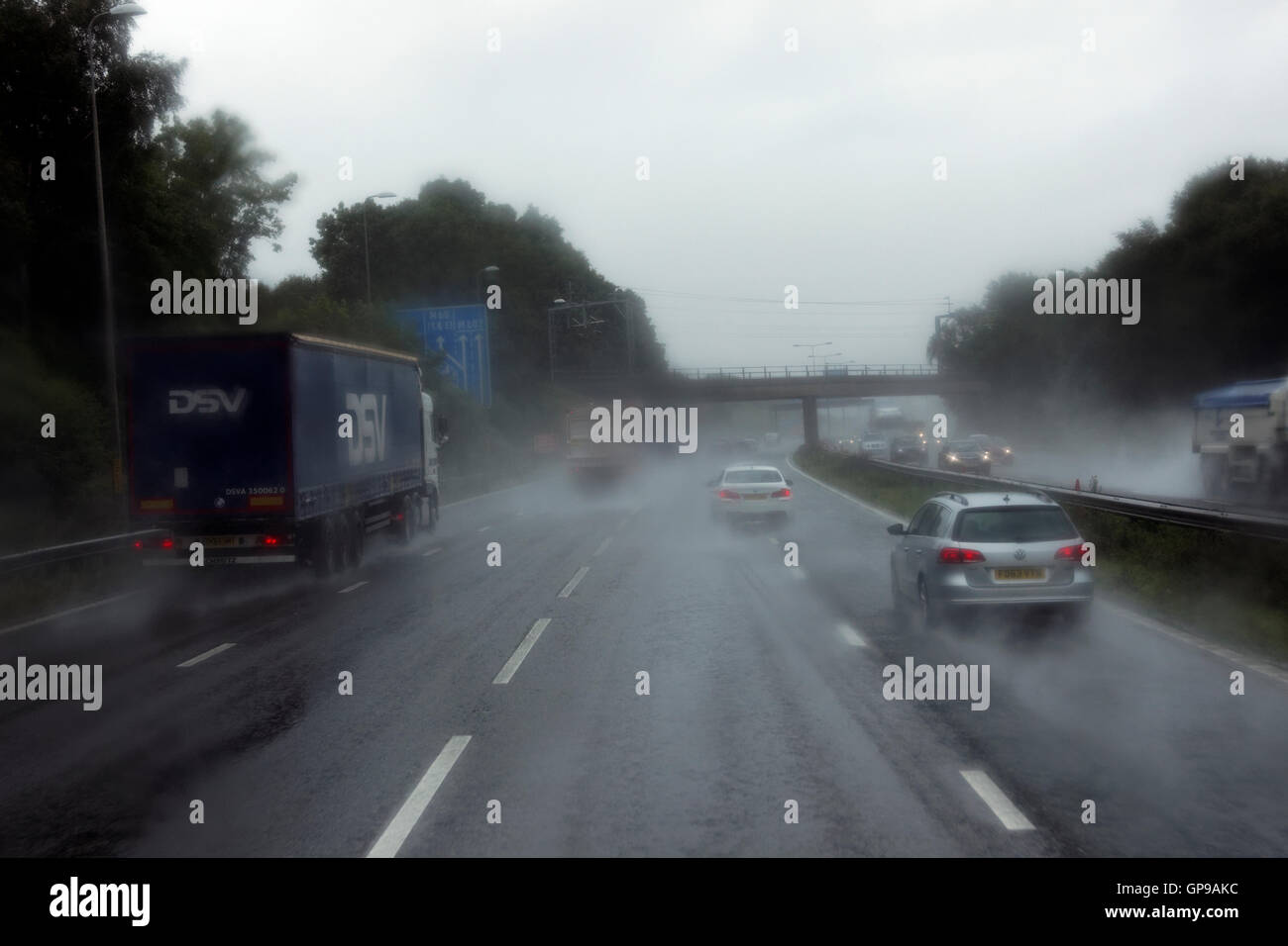 driving in middle lane on UK motorway in poor wet conditions surrounded by trucks and cars Stock Photo