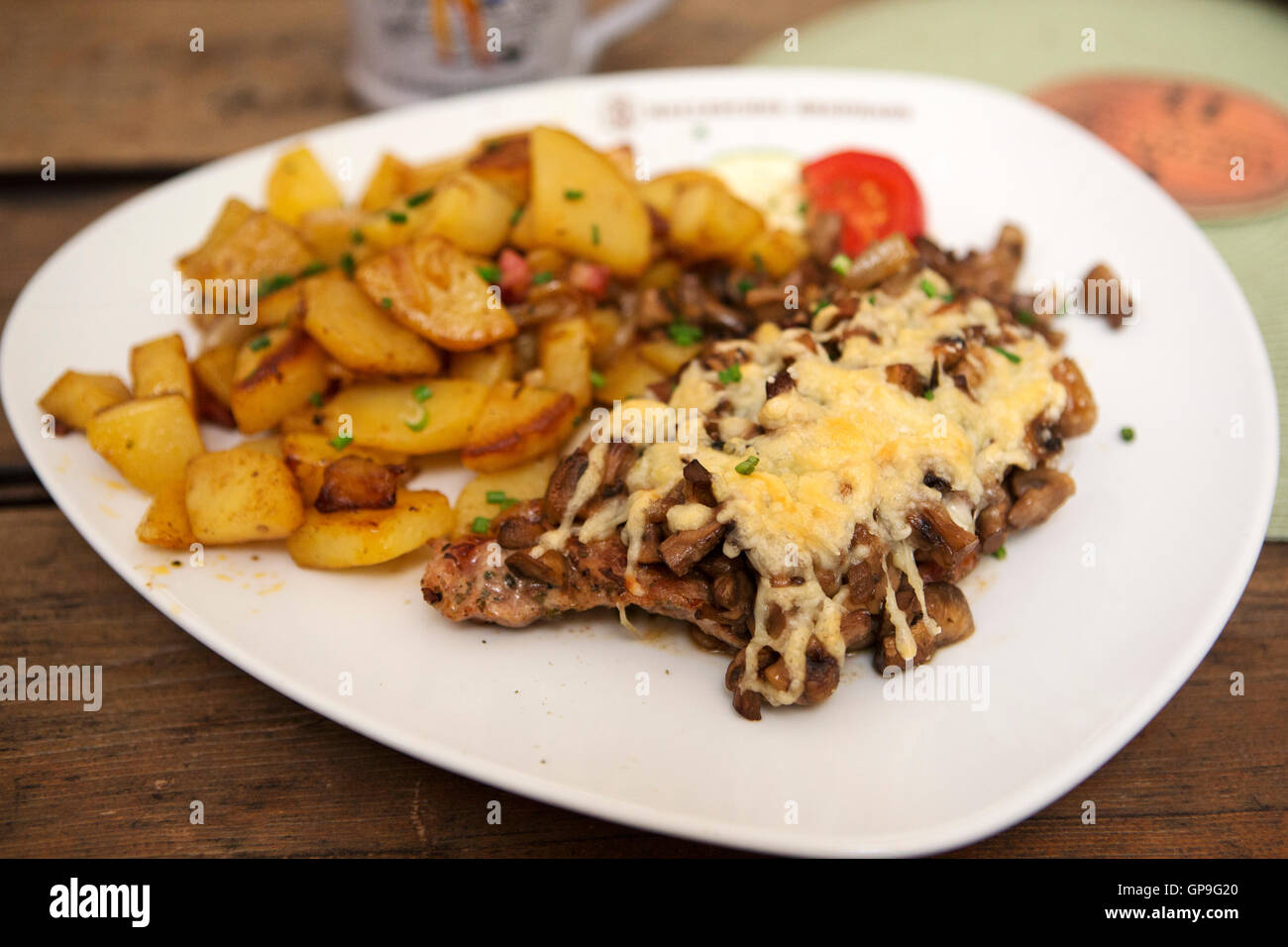 Pork steak served with cheese and mushrooms in Dresden, Germany. Bratkartoffeln (fried potatoes) are served with the dish. Stock Photo
