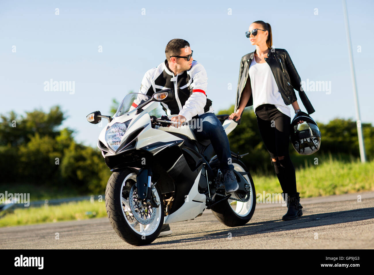 Man and woman wearing leather jackets and stylish sunglasses riding on motorcycle Stock Photo