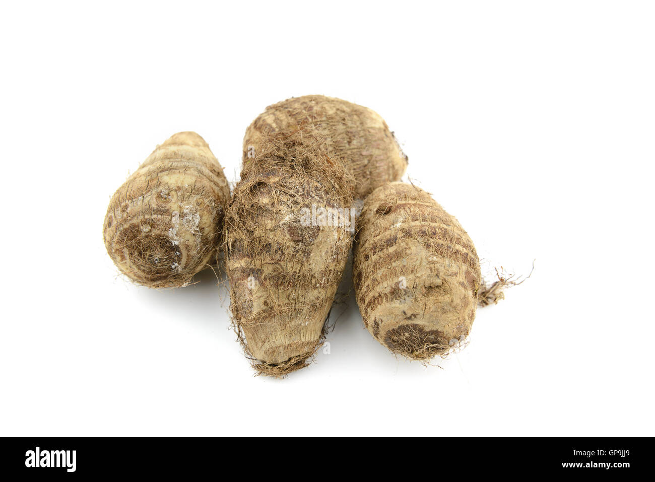 Pile of small brown taro with root hair on isolated white background Stock Photo