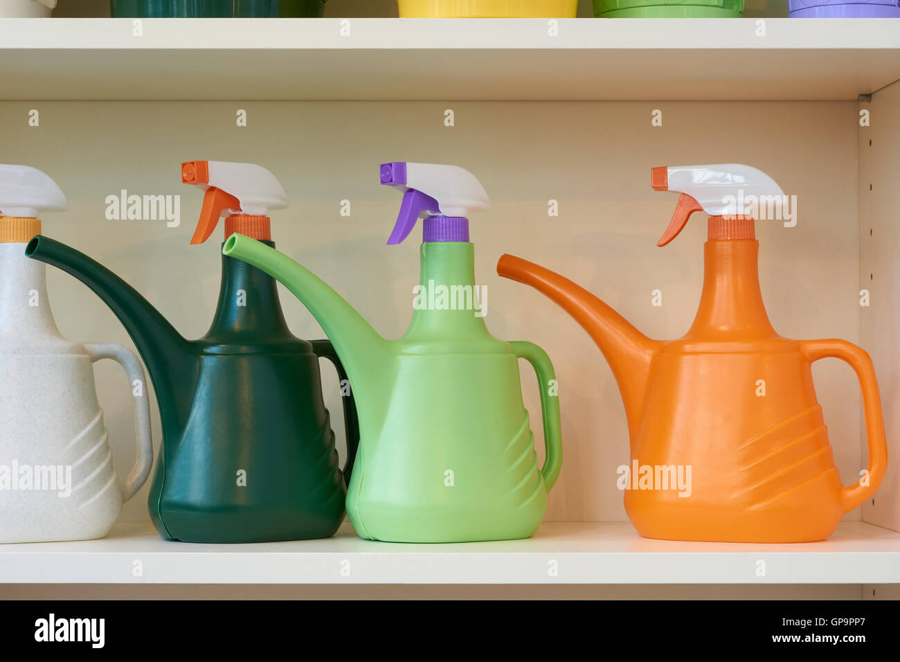 Combined watering cans and sprays on the shelf of the flower store Stock Photo