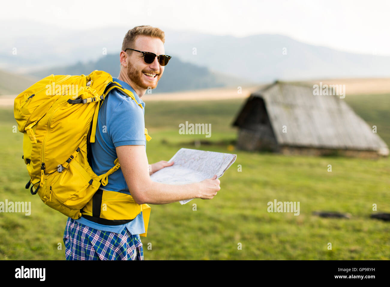 Young redhair man on mountain hiking holding a map Stock Photo