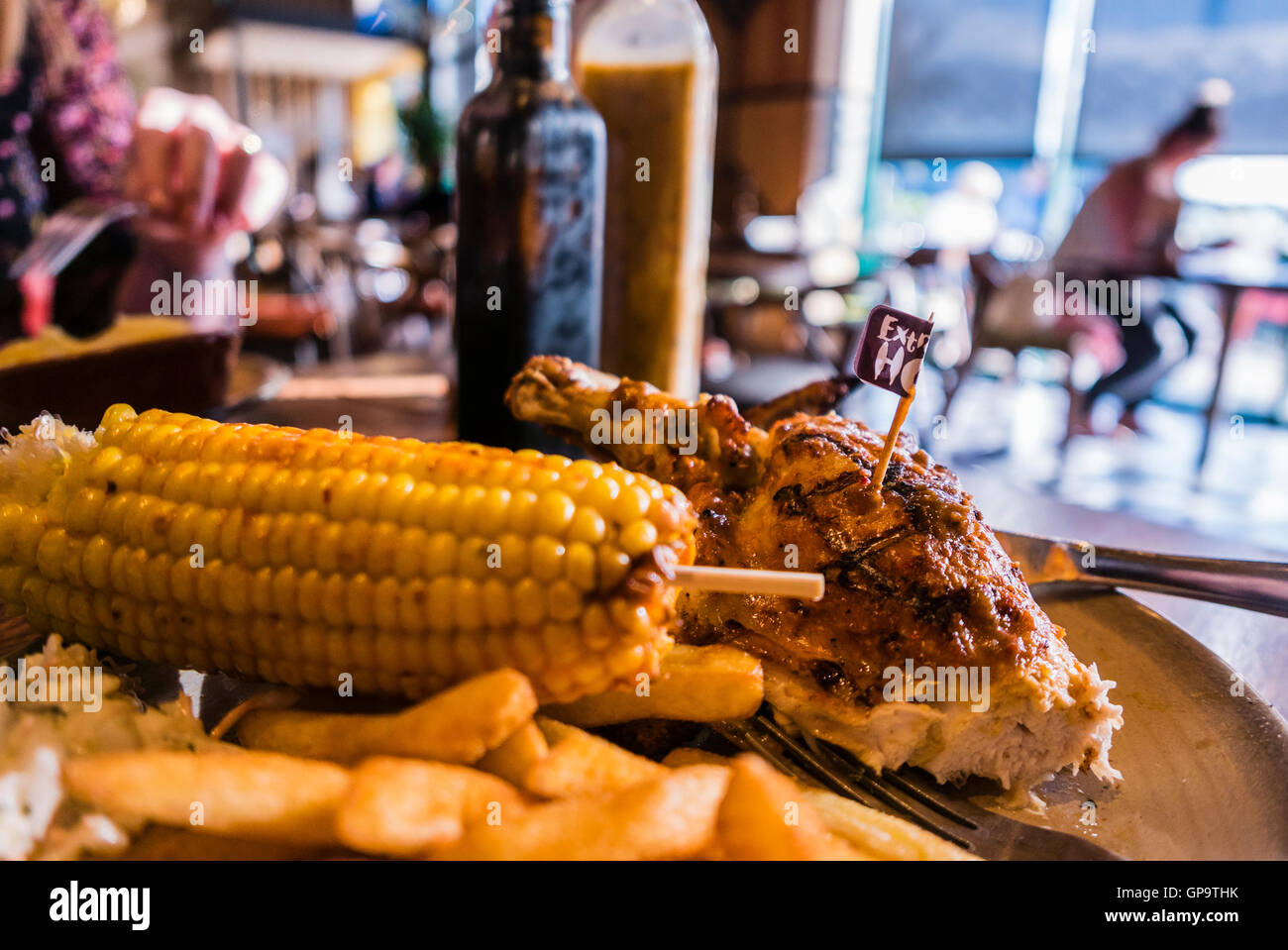 Extra hot chicken, chips and corn-on-the-cob on a table in a Nando's restaurant Stock Photo