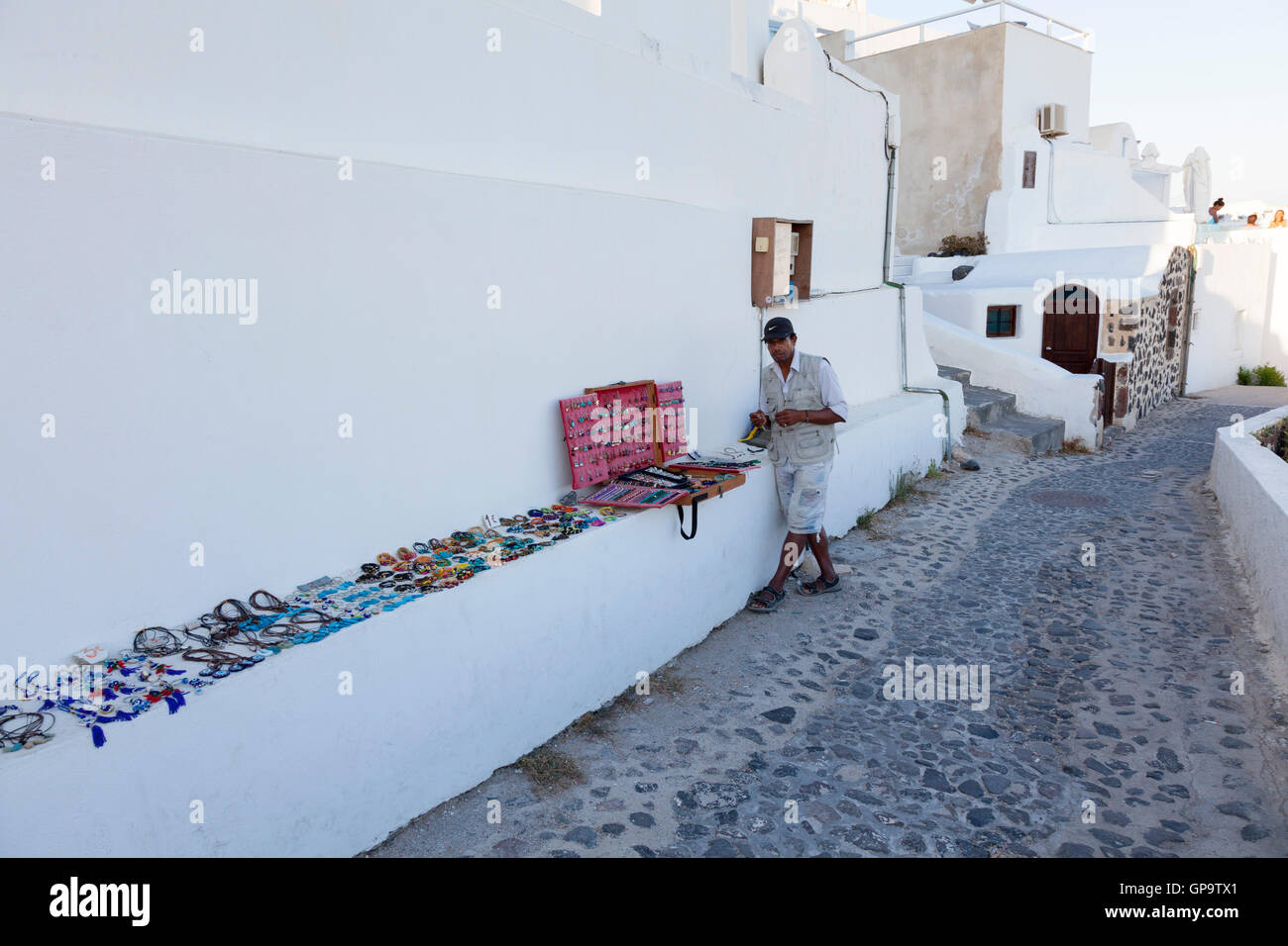 A street trader sells costume jewellery in Oia, Santorini in the Greek