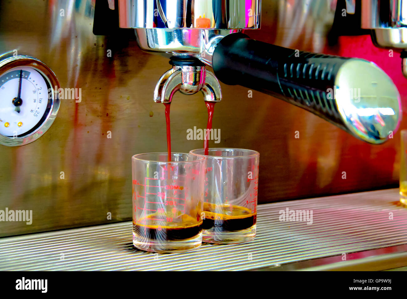 Close-up of espresso machine and shot glasses during a pour Stock