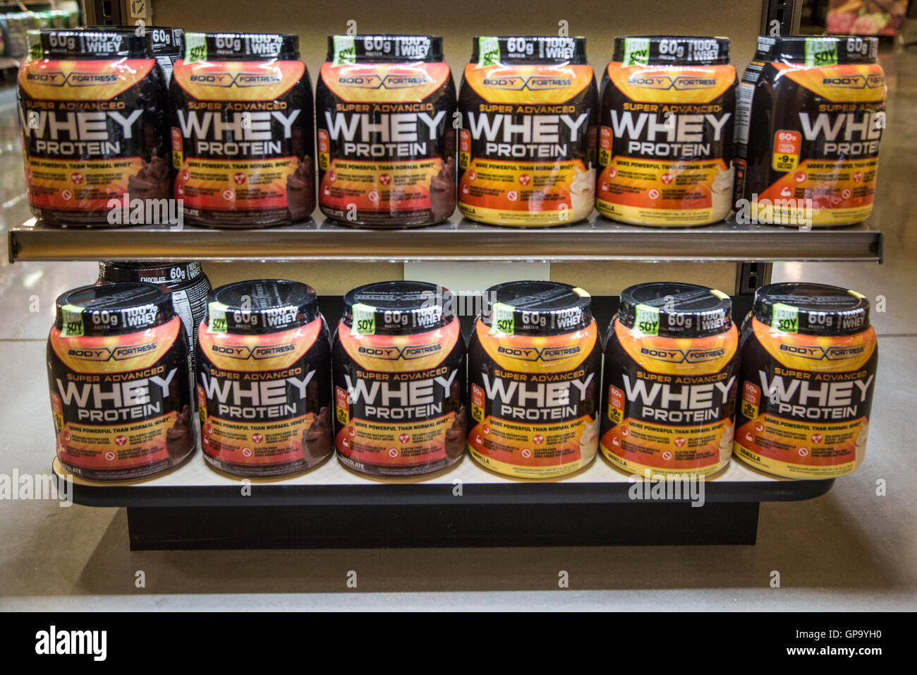 Large plastic containers of whey protein for sale on the shelves of a health food store. Stock Photo