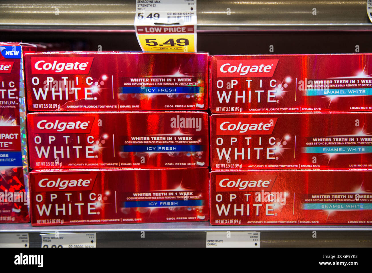 Stacks of Colgate toothpaste boxes on display on shelves at a grocery