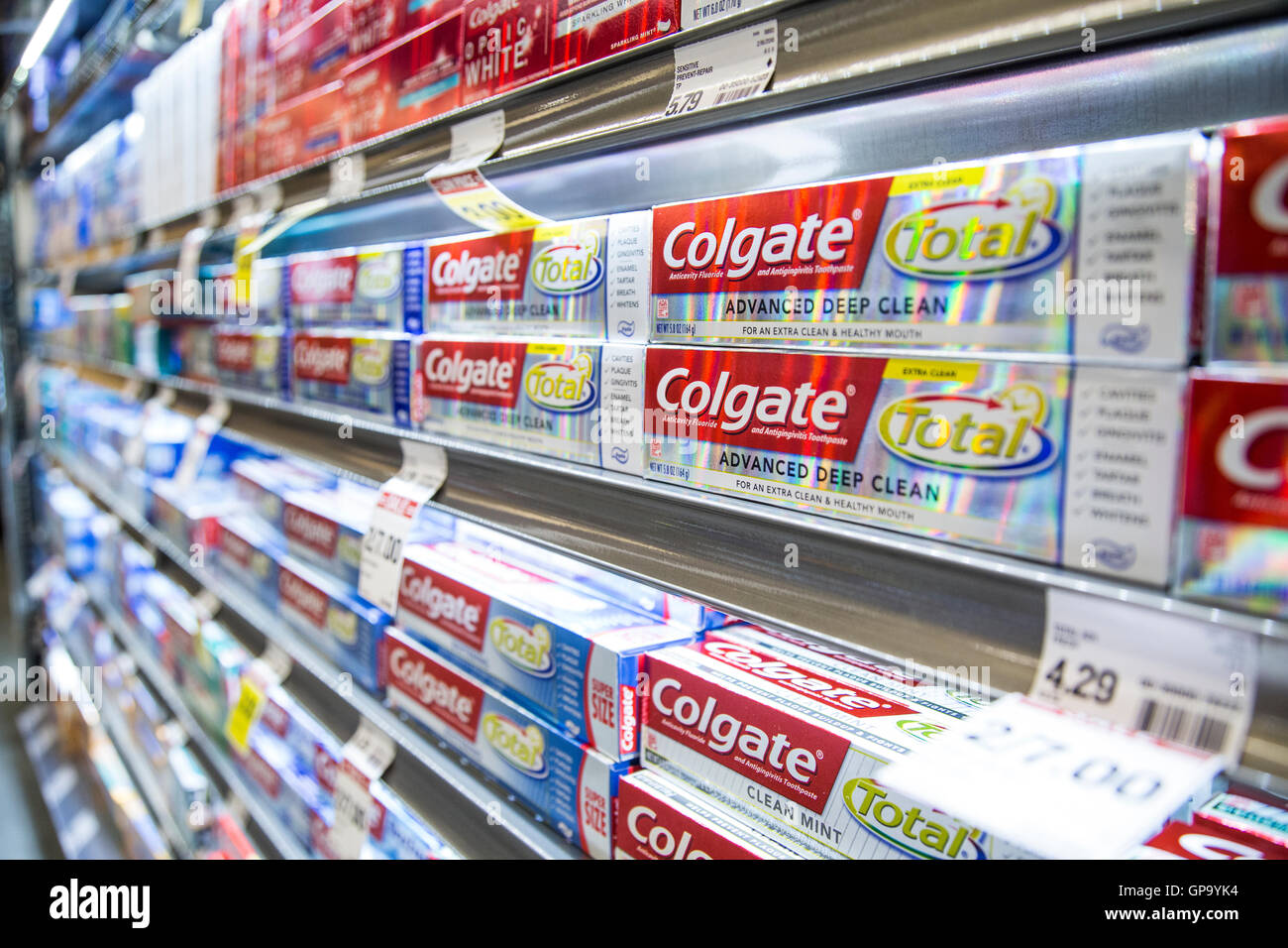 Stacks of Colgate toothpaste boxes on display on shelves at a grocery