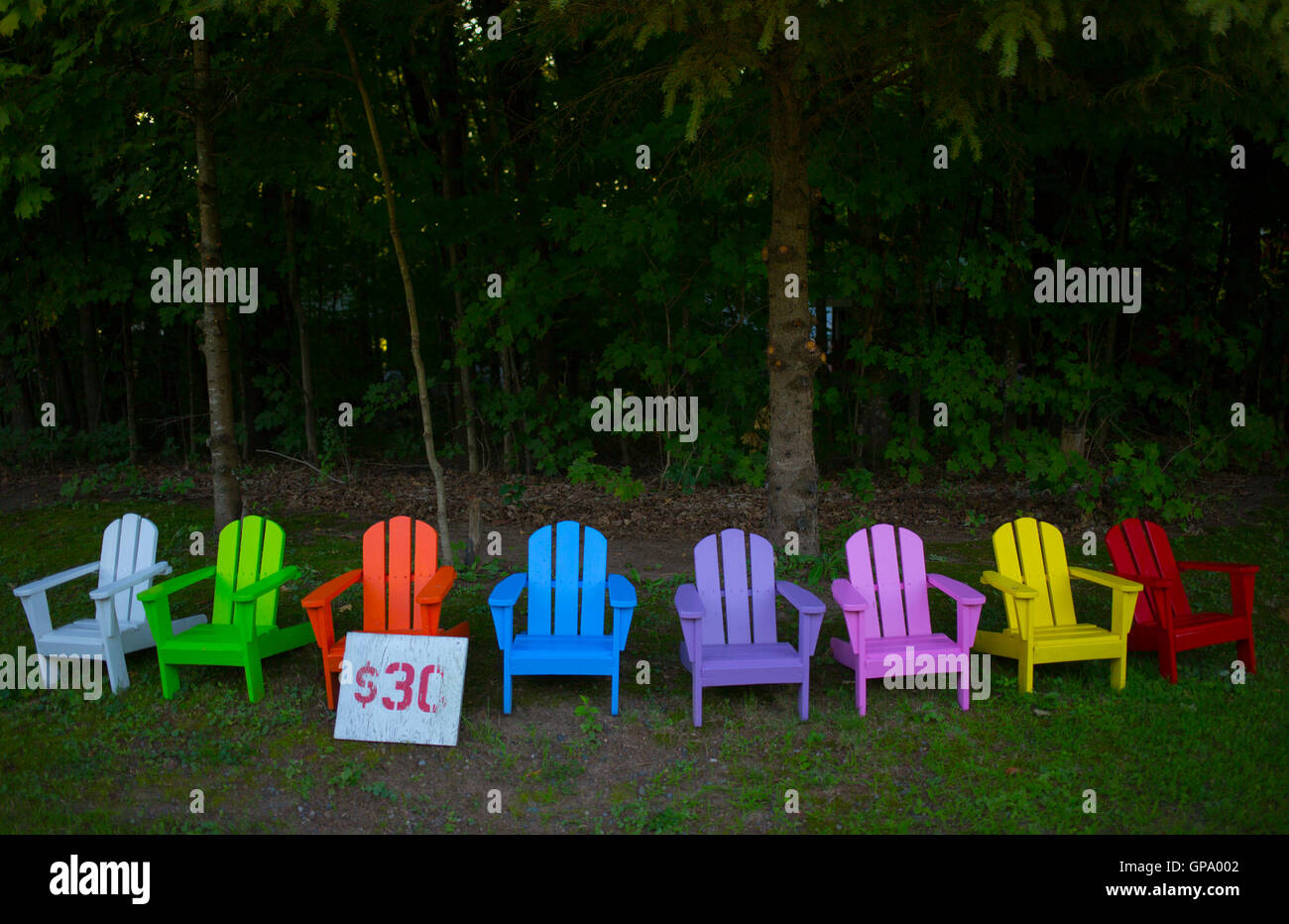 Brightly coloured chairs are displayed for sale outside of a workshop on the side of a road near Aitkin, Minnesota, USA Stock Photo