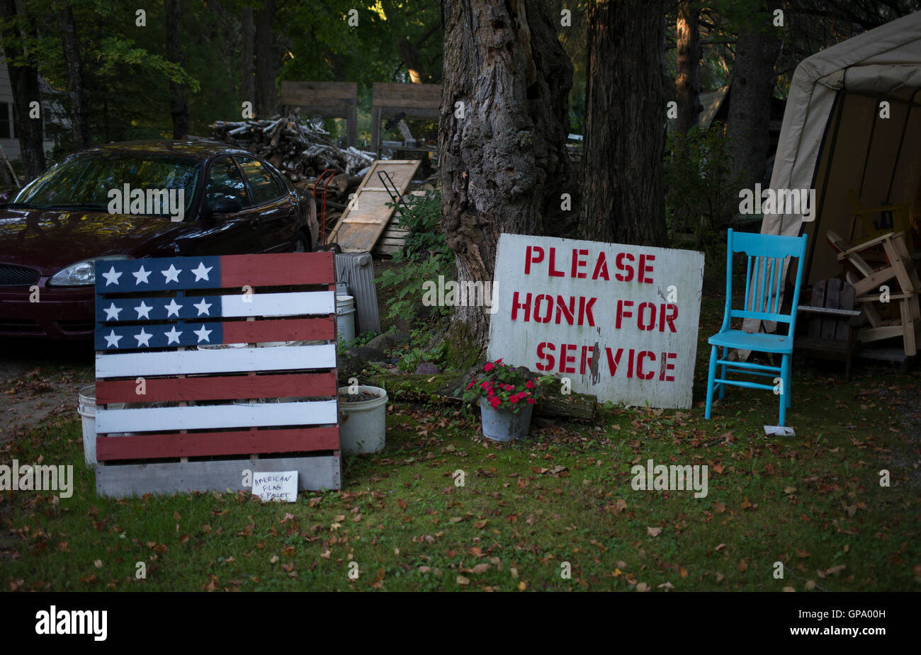 An American Flag and furniture are displayed for sale outside of a workshop on the side of a road near Aitkin, Minnesota, USA Stock Photo