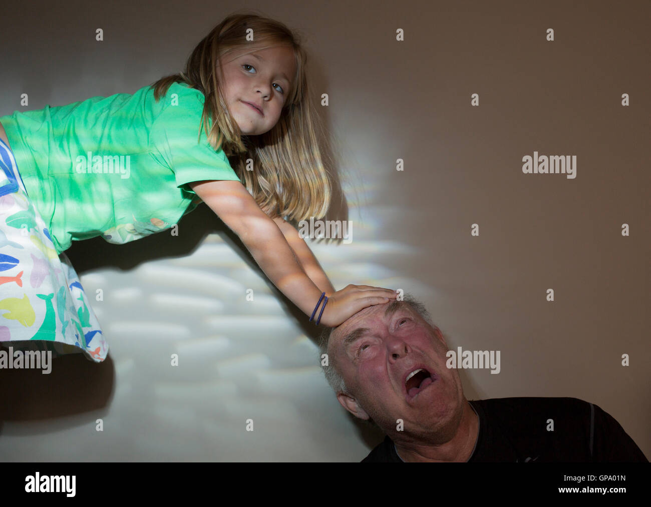 A young girl plays with her grandfather Stock Photo