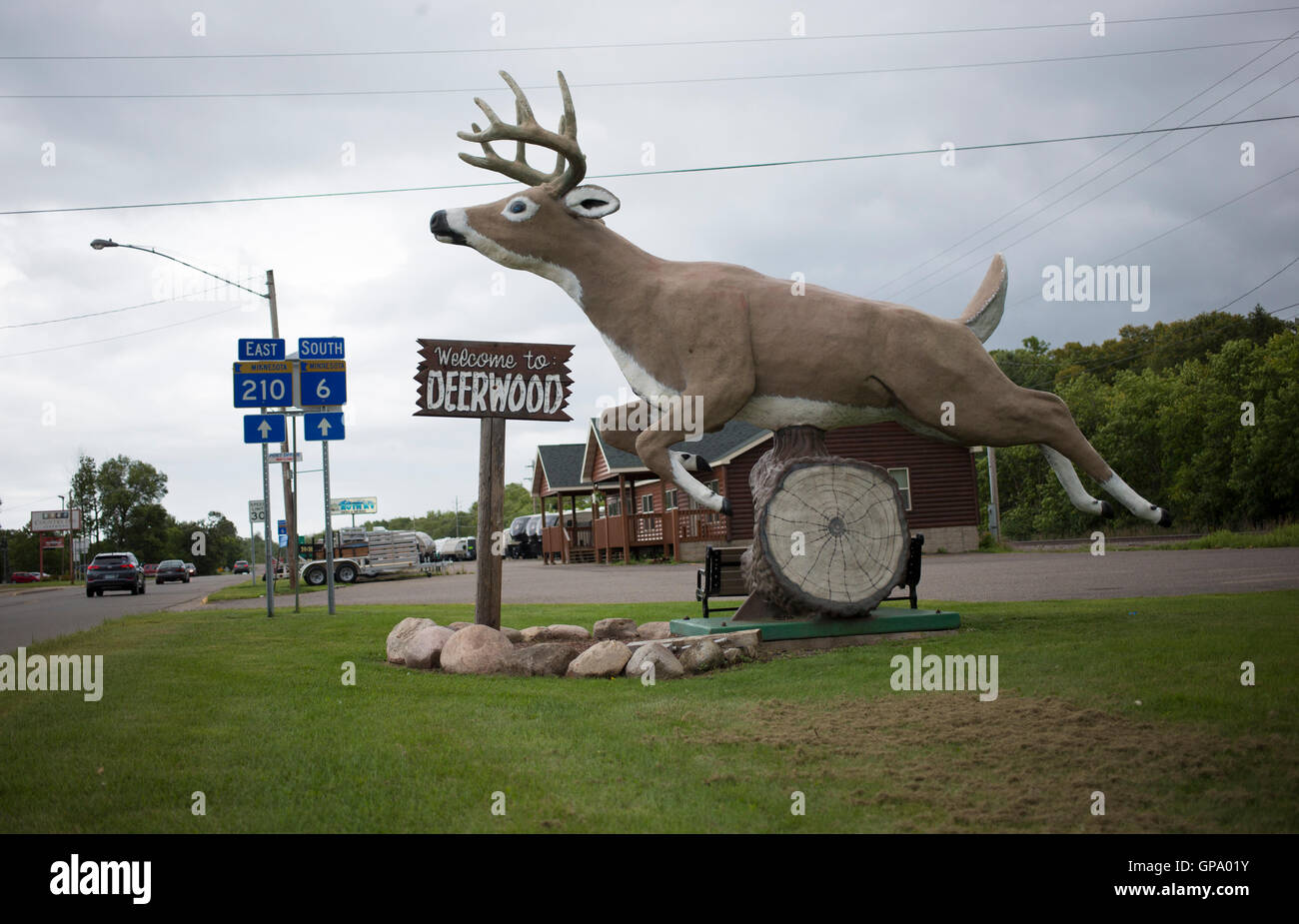 A statue of a deer is seen by a sign welcoming drivers to Deerwood, Minnesota Stock Photo
