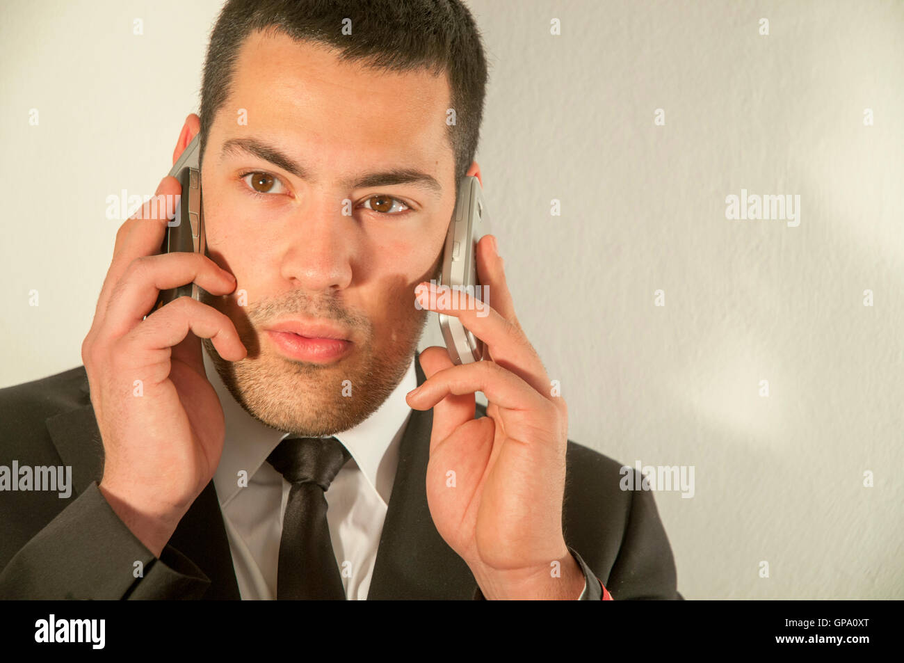 Young man using two mobiles phones. Stock Photo