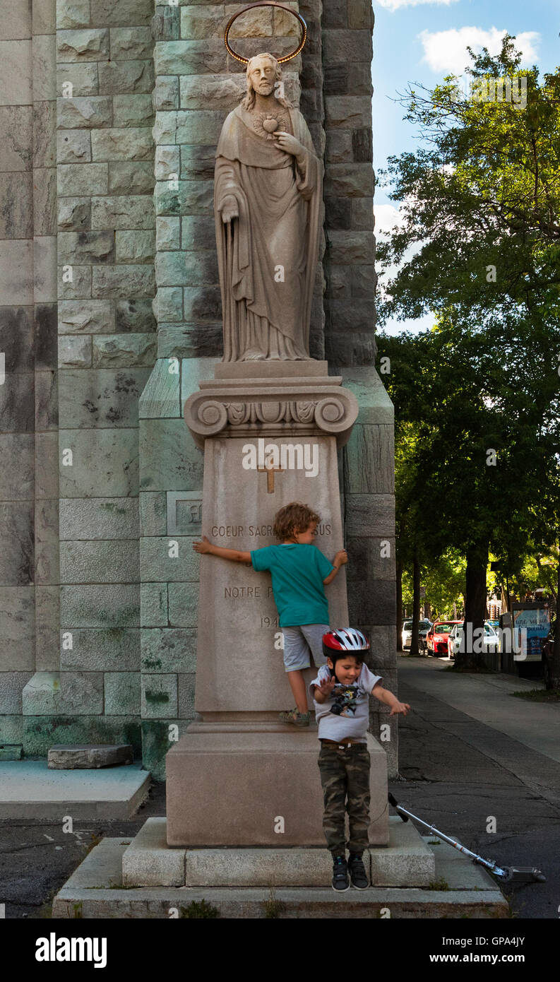 Children playing in front of the statue of Christ in front of a church, Montreal. Stock Photo