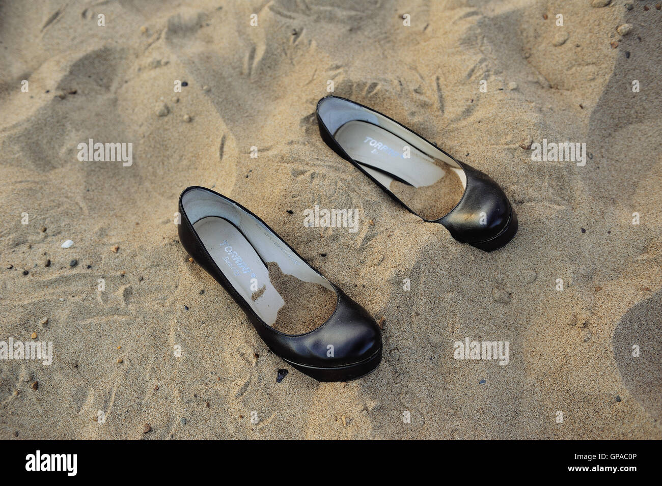 Pair of women's shoes while walking on a sandy beach. Inside shoes pour