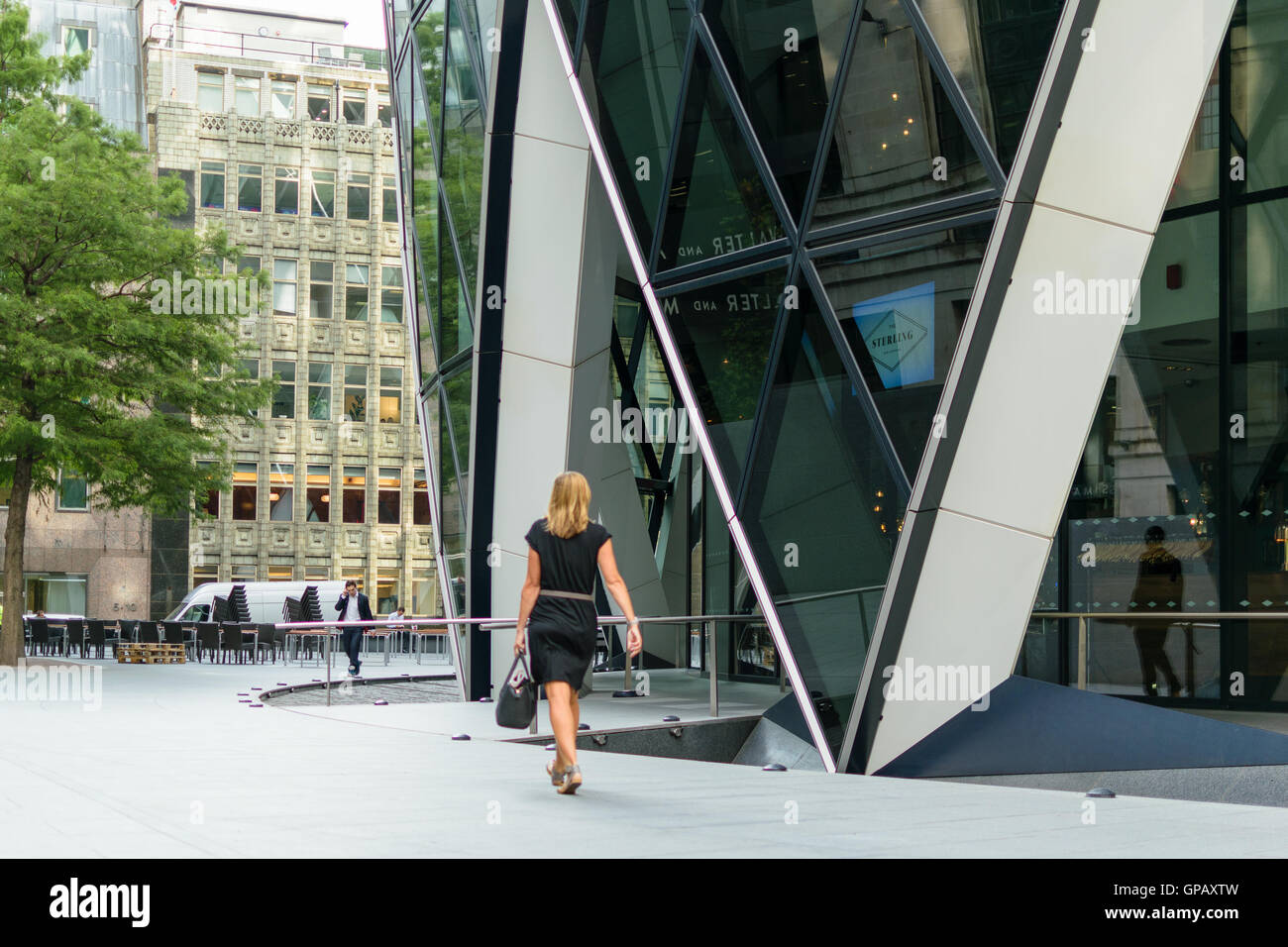 London, England - 31 August 2016:An unidentified business woman walks pass the Gherkin building in City of London Stock Photo