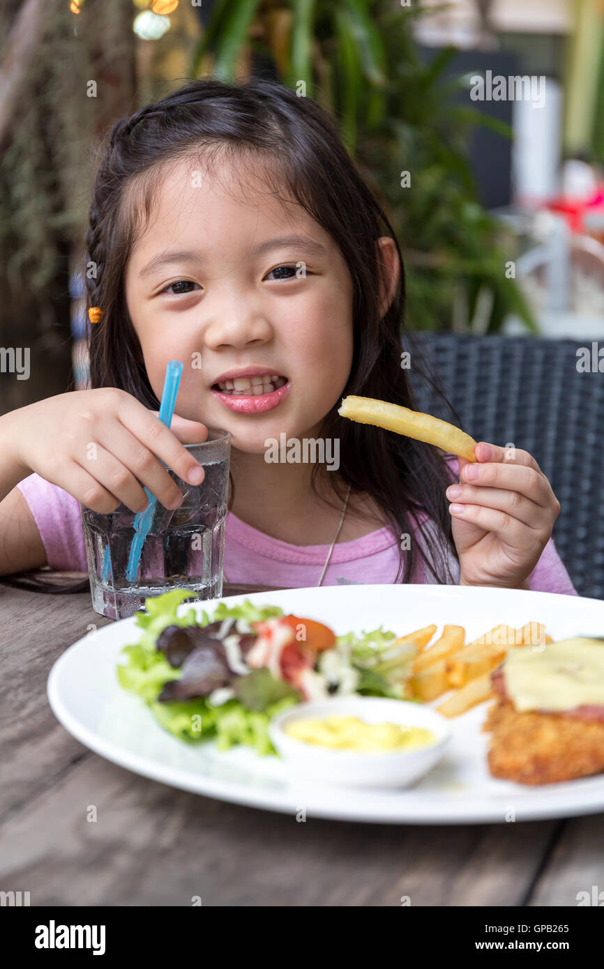 Child eating steak and fries at restaurant. Stock Photo