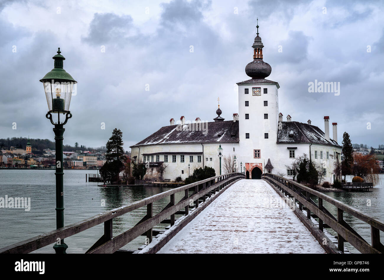 Snow covered wooden bridge leading to a white church on a lake island in Gmunden near Salzburg, Austria Stock Photo