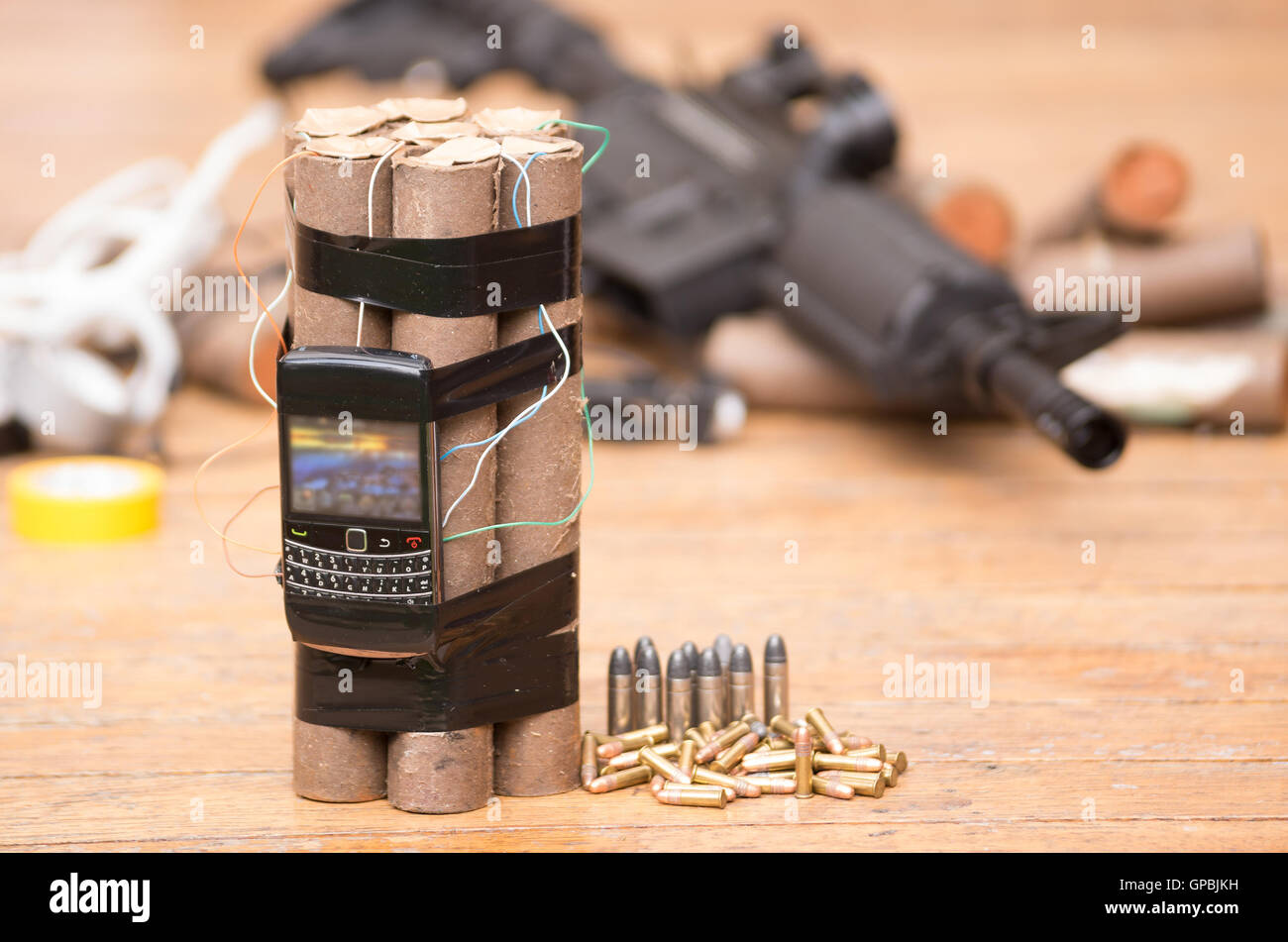 Homemade bomb with explosives and cellular phone attached wires sitting next to ammunition, machine gun in background. Stock Photo