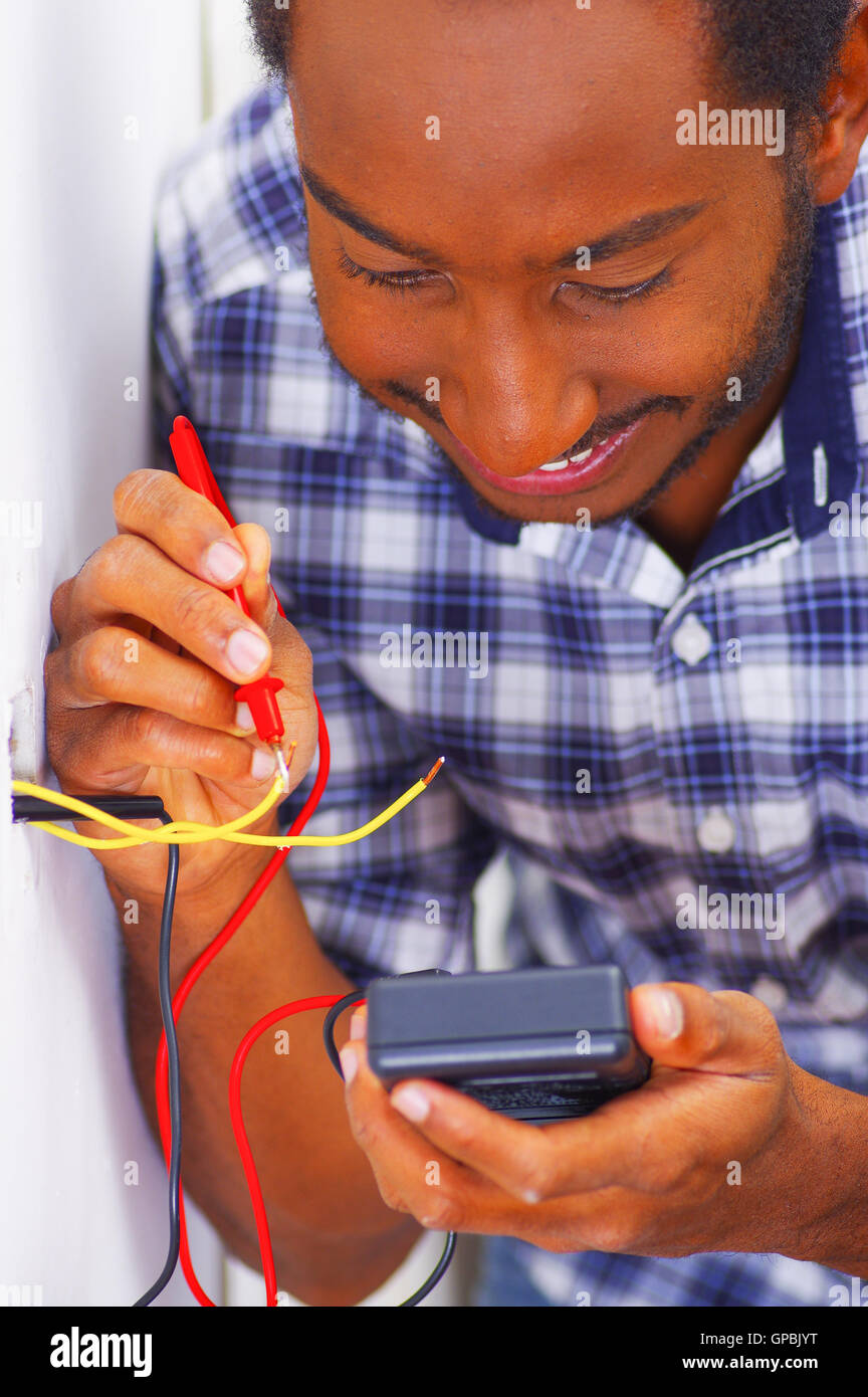 Man wearing white and blue shirt working on electrical wall socket