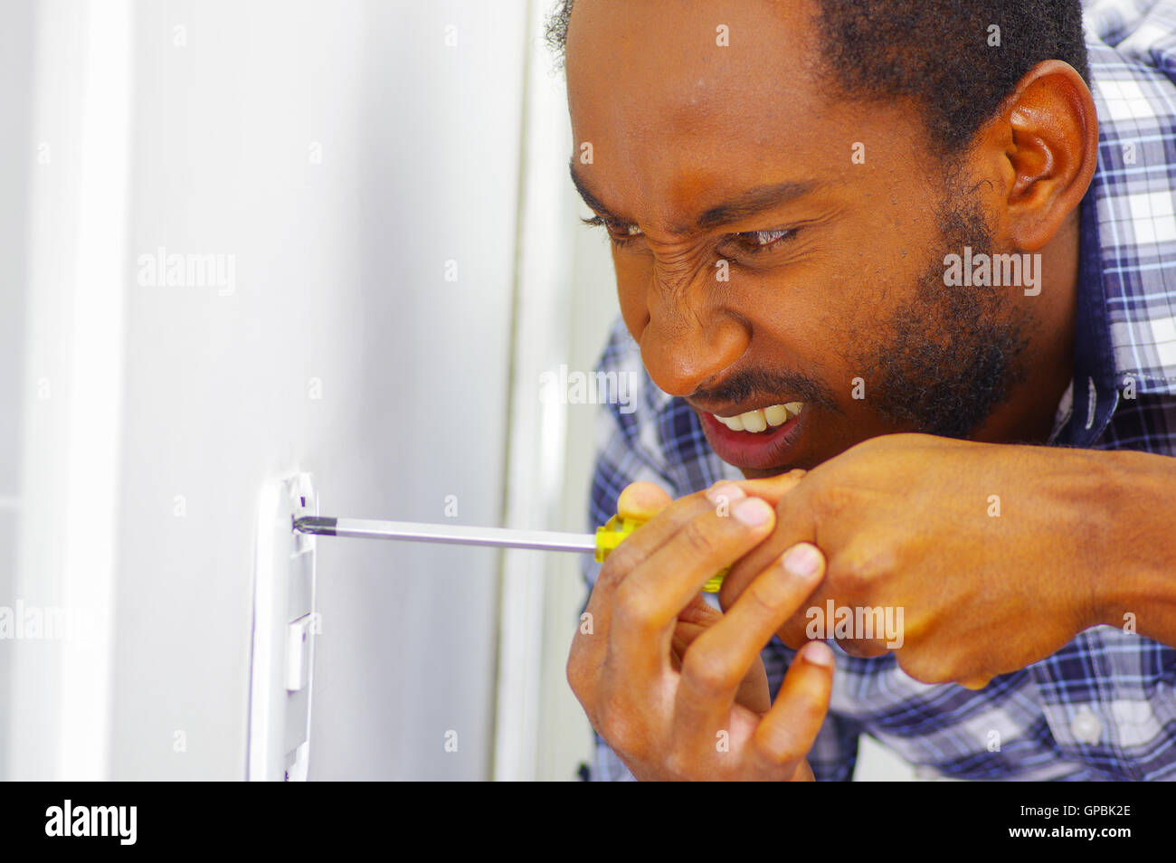Man wearing white and blue shirt working on electrical wall socket ...