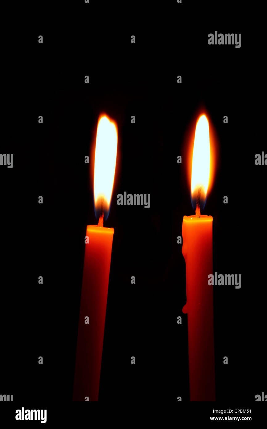 two burning candles on a black background Stock Photo - Alamy