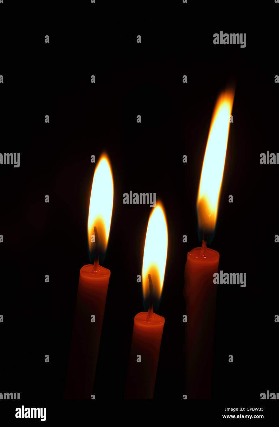 three burning candles on a black background Stock Photo - Alamy