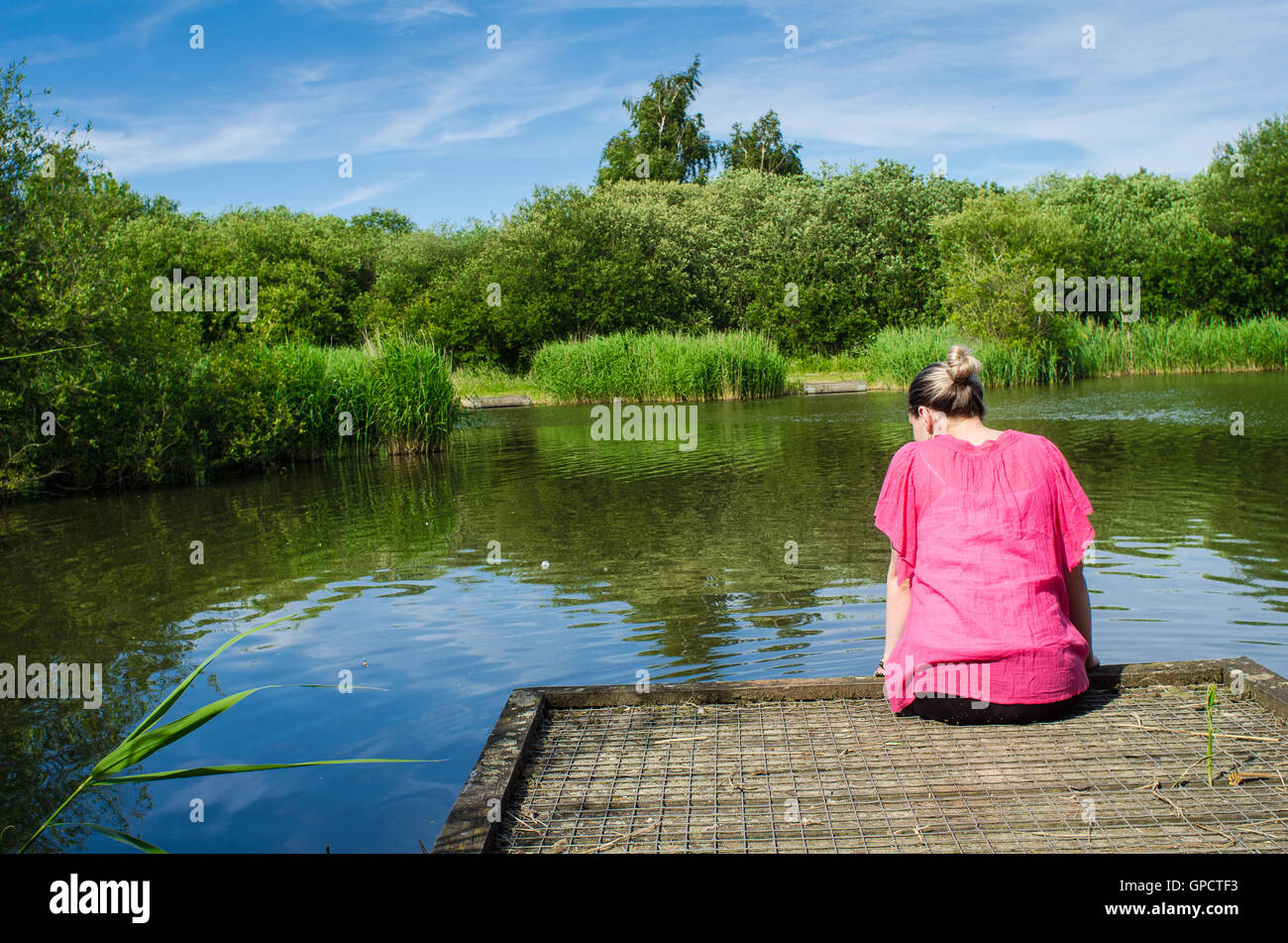 woman in pink by the pond Stock Photo
